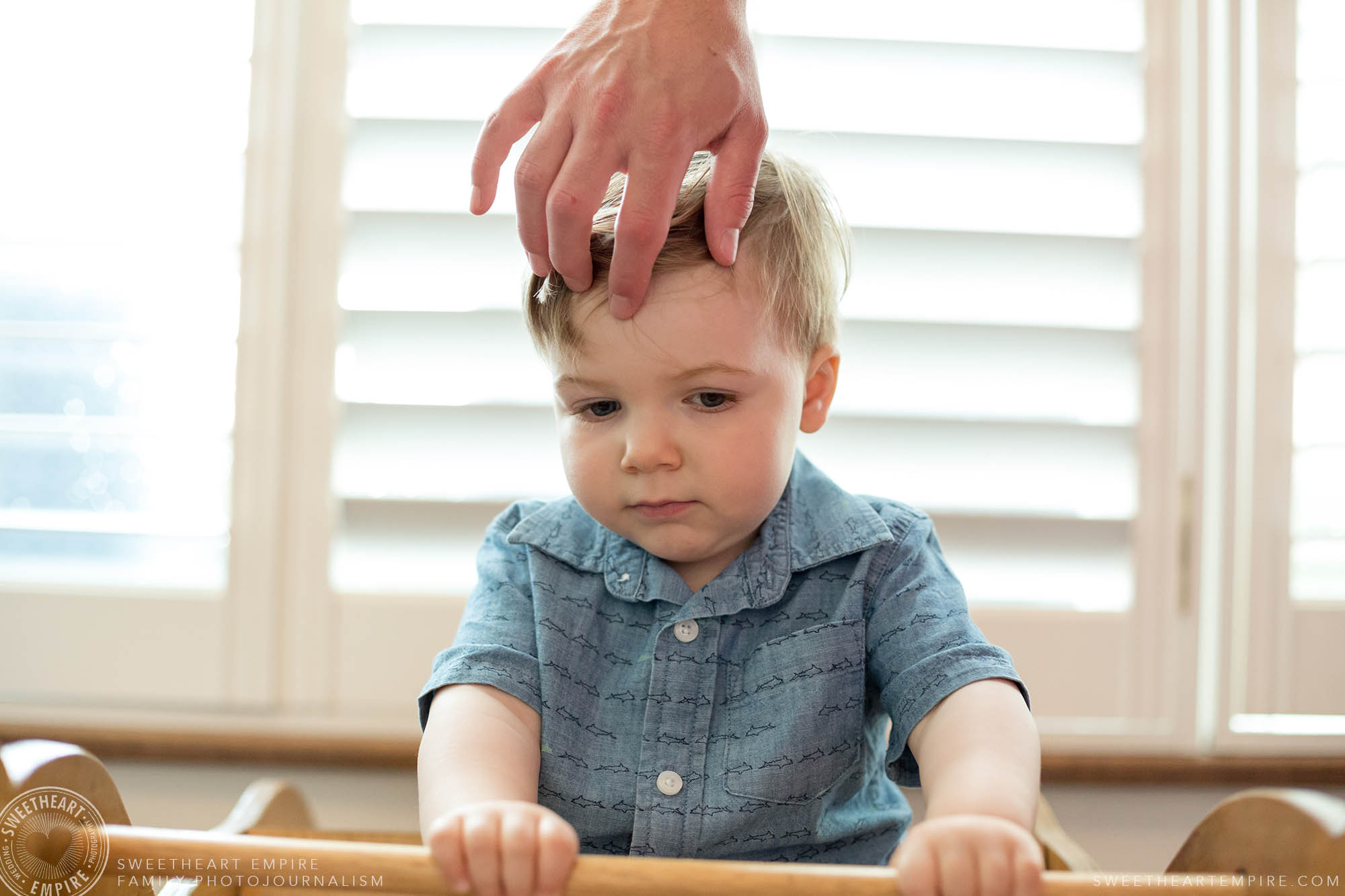 15_Fathers hand fixing toddlers hair while the child concentrates on rocking the rocking hourse.jpg