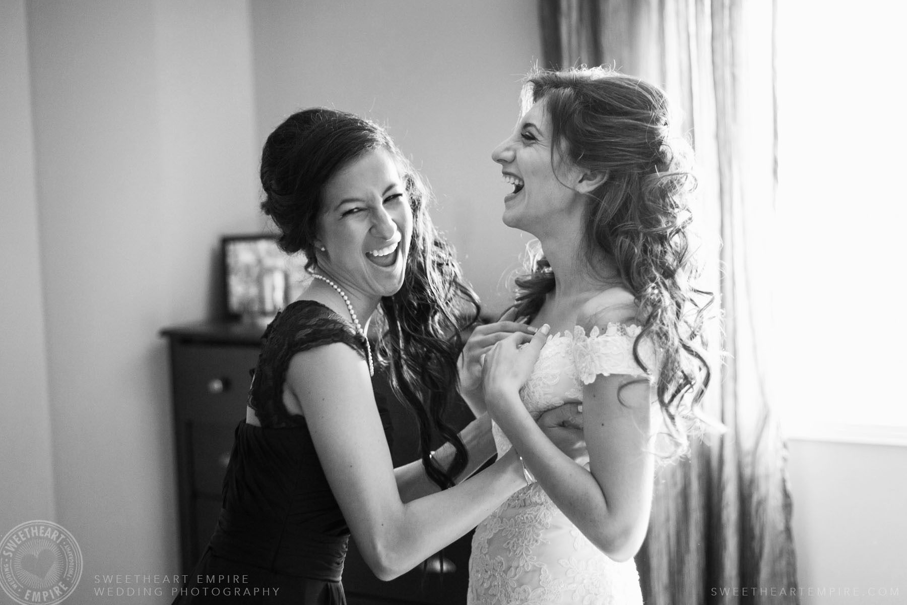 Bride getting help from her bridesmaid while getting dressed; Eagles Nest Golf Club Wedding Photos