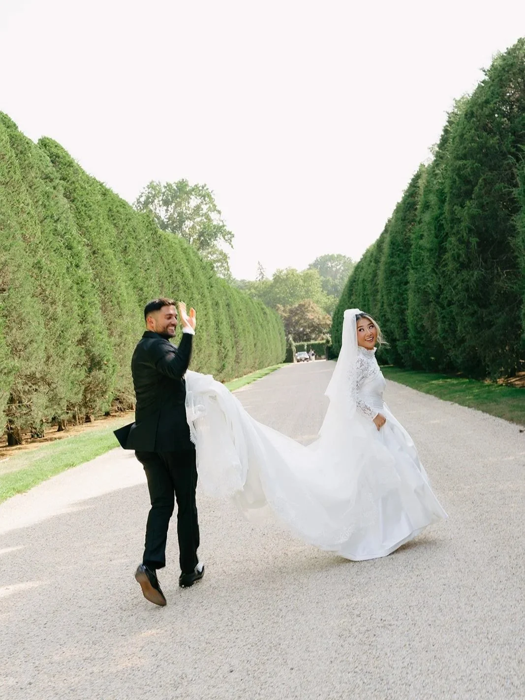 bride and groom running in oheka castle driveway entrance