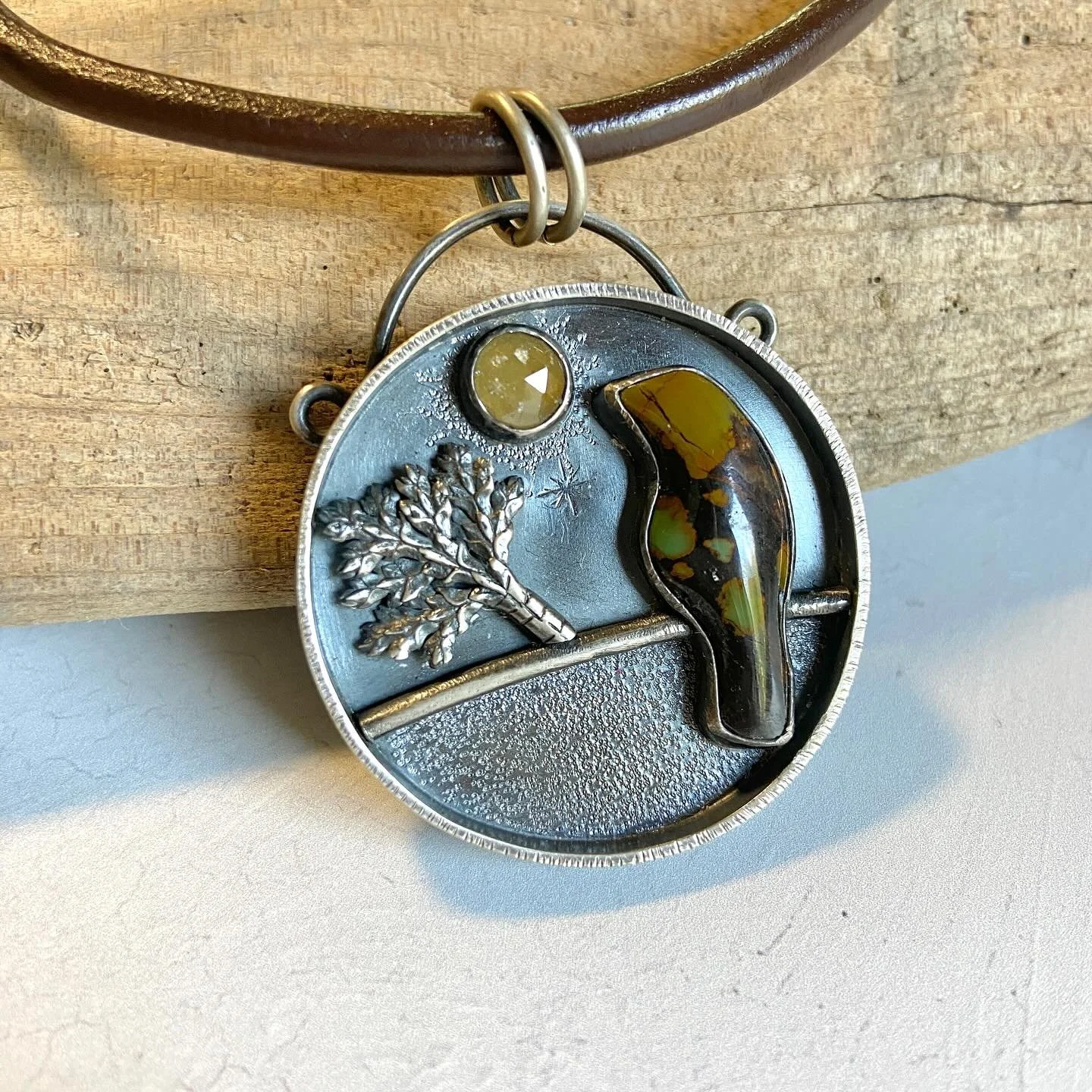 This big silver pendant features a turquoise crow and a rose cut sapphire on a thick brown leather cord with silver end caps and a lovely chunky lobster clasp. This is truly a one-of-a-kind.  Shown pictured on an AI model in pictures one and two. 

#
