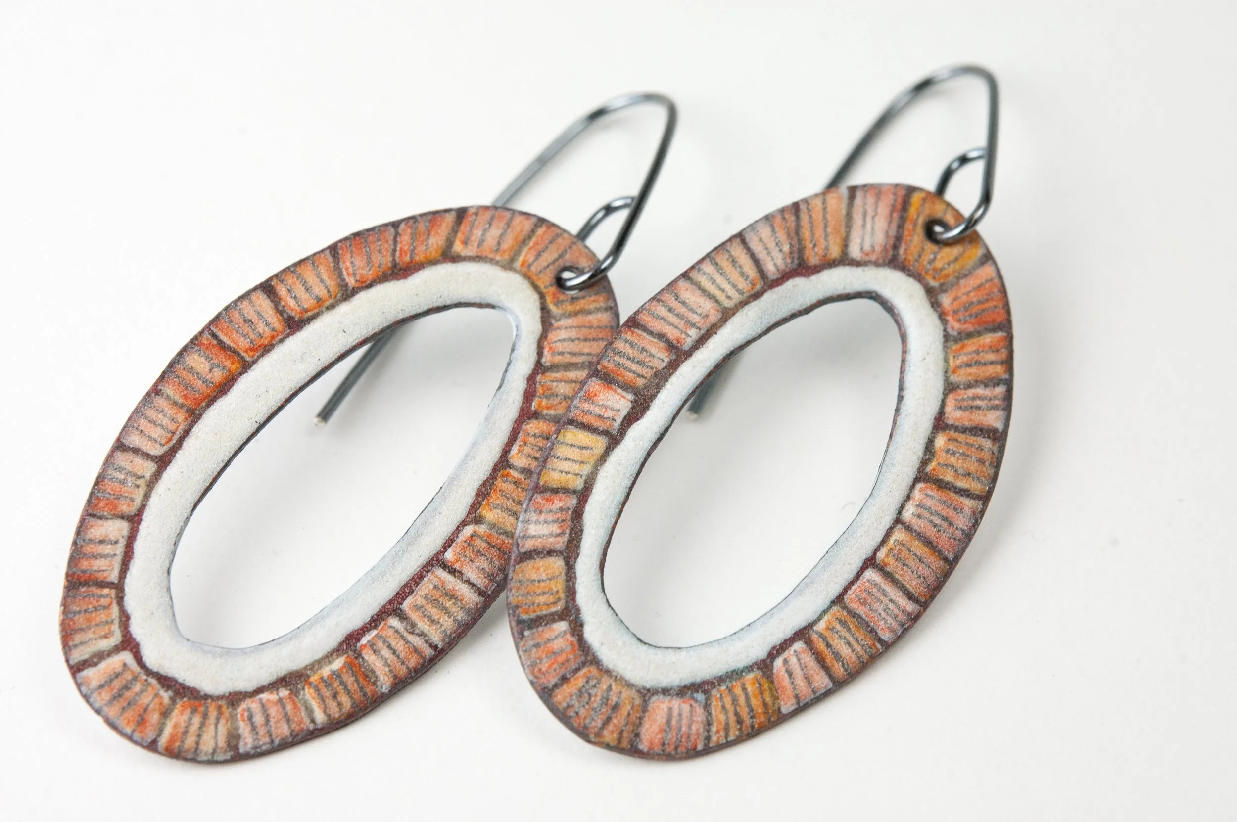 A pair of oval enameled hoops with sgraffito and graphite pencil details
