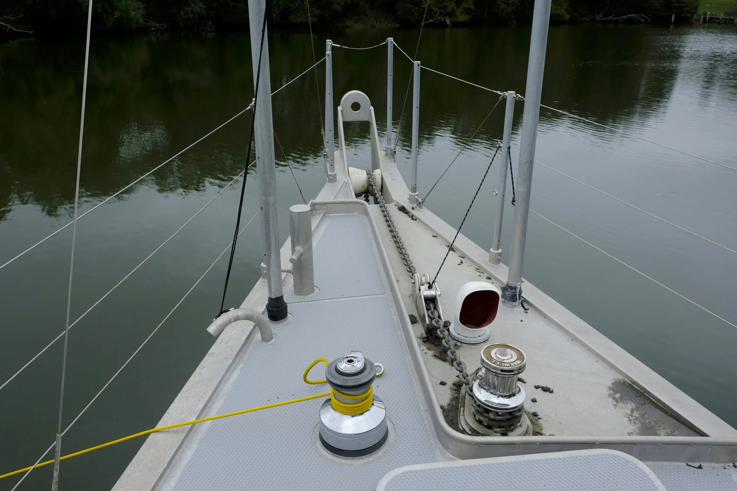 The mud dam keeps the mud and slime off the foredeck, as the boat does not use a washdown pump to clean the chain rode and anchor. It washes off naturally, and the chain in the chain barrel under the foredeck drains overboard.  The extended section in front of the bow is strong enough to hold the boat against a dock, and for use with a parachute anchor if they want to reduce motion in a seaway. It also allows the boat to pivot with a line from it to a dock bollard midships. Put the boat in forward gear and the boat's stern swings out away from the dock for a clean departure from a crowded dock even in crosswinds.  The curved pipe on the port side of the bow is the forward bilge pump discharge, and any water being pumped from the forward bilge is easily seen from the helm.