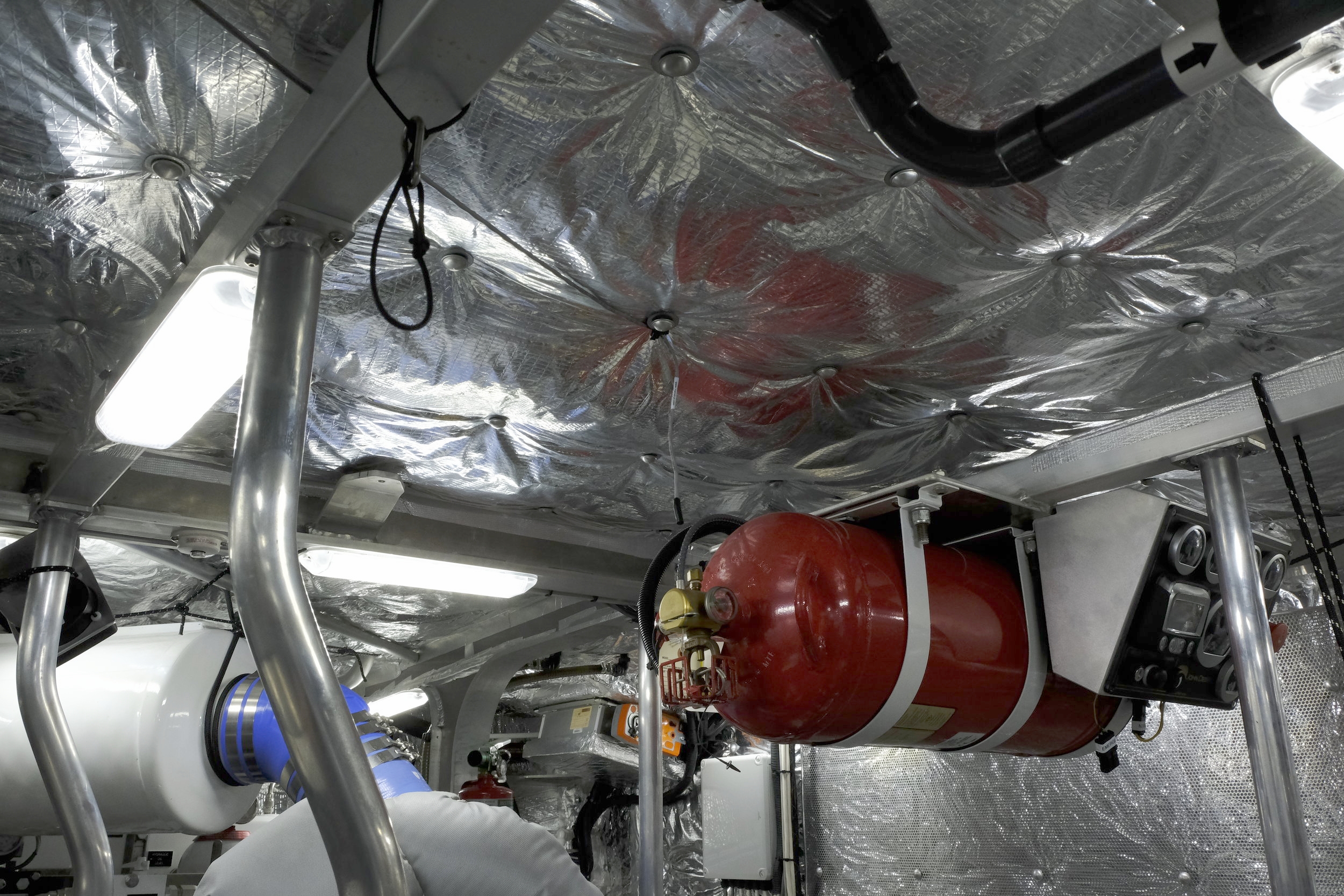 Two full-size Halon bottles mounted in the engine room ensure swift response to any fire threat. Steve says each is fully sized for the entire engine space, but he would never rely on just one system to do the job, in case someone opens a hatch or otherwise compromises the ability of the single bottle to handle a fire. The second is a critical backup...just in case.  Note the electrical connectors hanging down from one of the engine control panels. In case of electronic engine control failure, manual controls can be plugged into these connectors, bypassing the normal electronic controls for throttle and other functions.