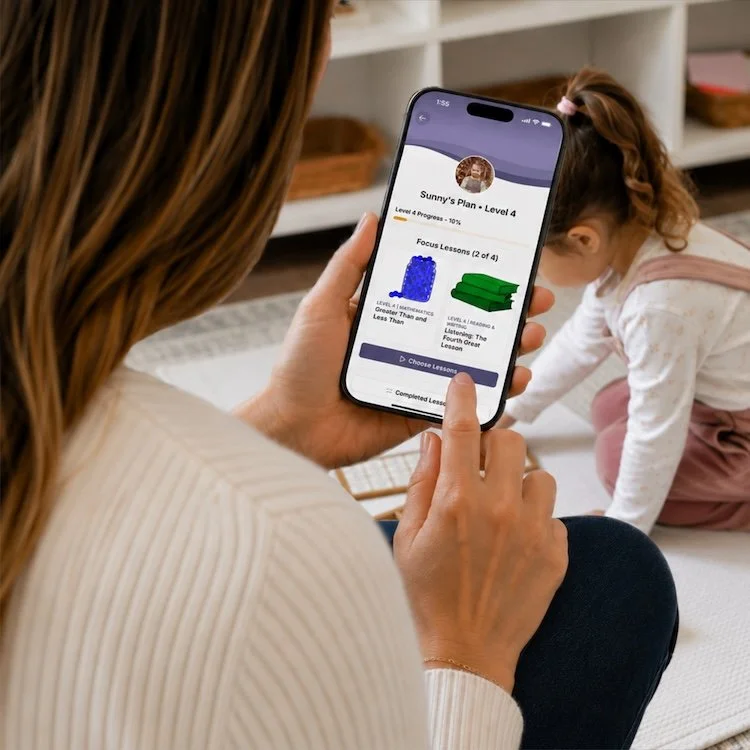 A homeschooling mom using The Child of the Redwoods App while her child does a work on a rug in a Montessori at home room.