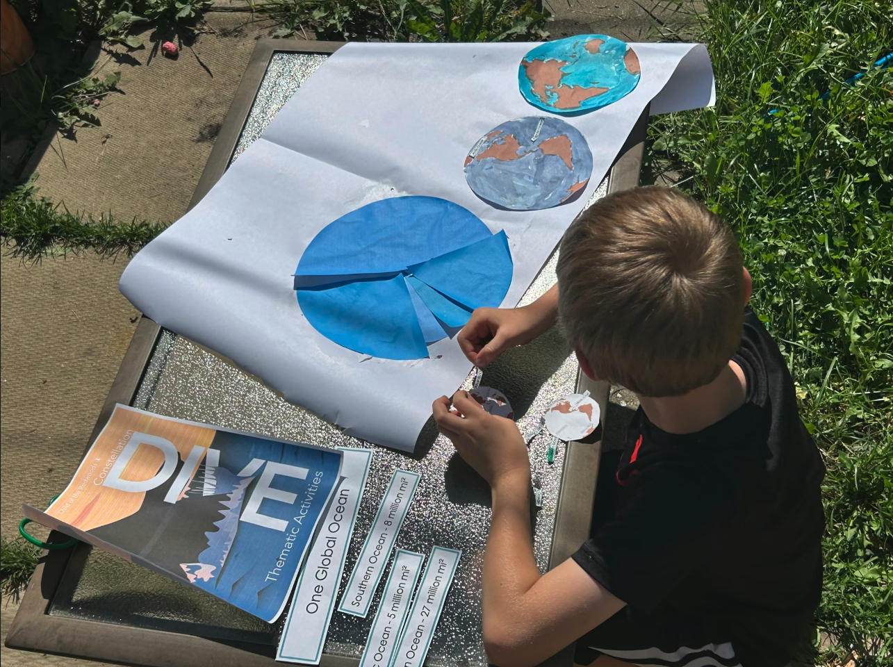 child working on Montessori geography activity about global oceans at outdoor homeschool table