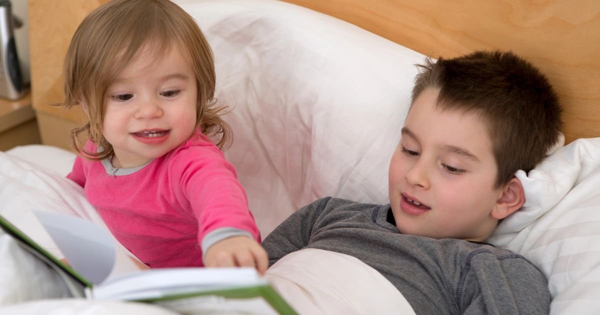 Toddler and preschooler learning to read together in bed