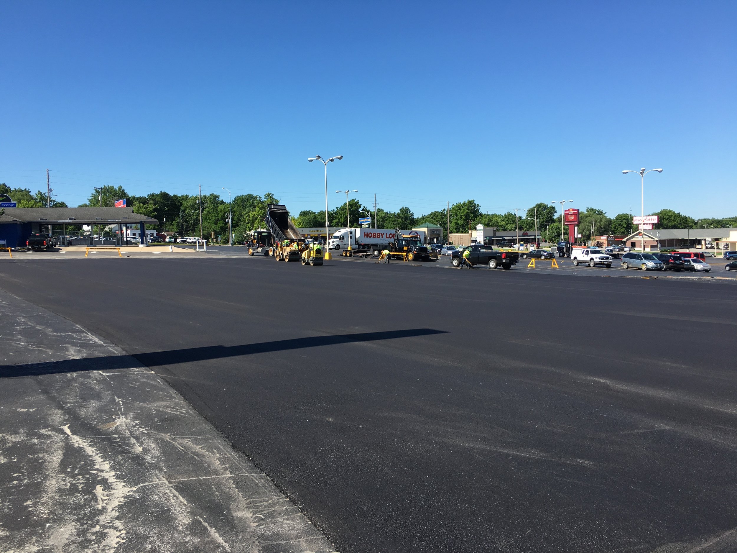 Springfield Striping &amp; Sealing team in action, sealcoating a spacious parking lot for a fresh, durable finish near Springfield, MO.
