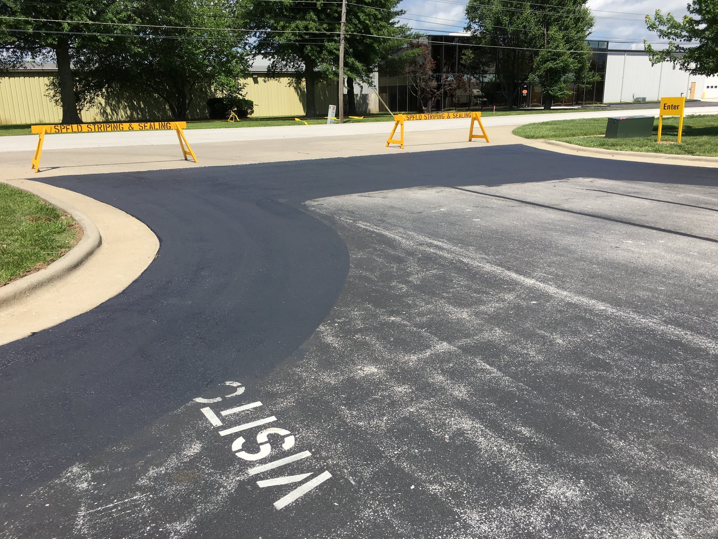 A parking lot approach where Springfield Striping and Sealing has squeegee applied sealer in order to increase the durability of high traffic areas.