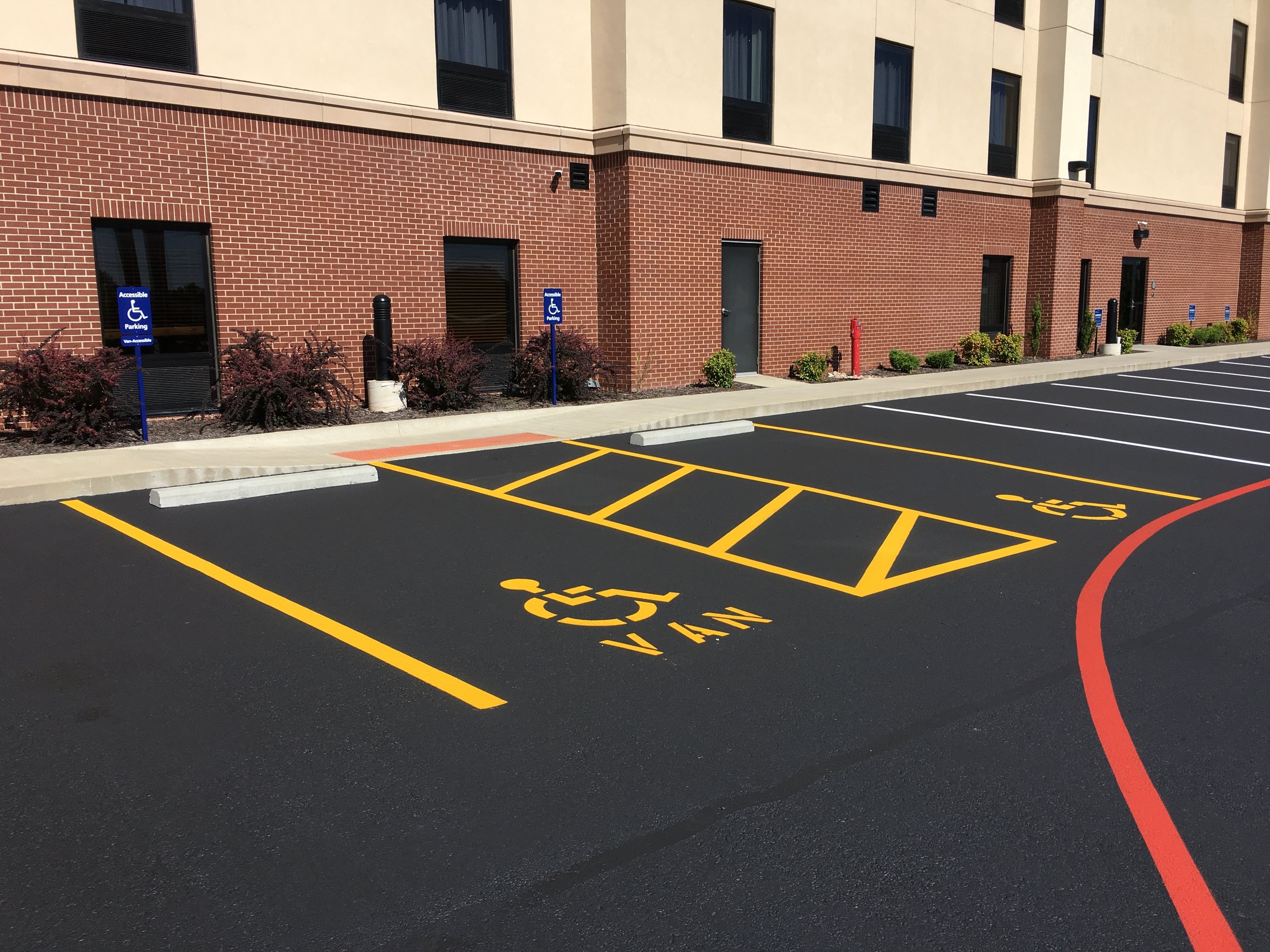 Newly completed parking lot by Springfield Striping and Sealing. The lot includes multiple handicap-accessible spaces marked with yellow lines &amp; symbols complemented by blue signage.