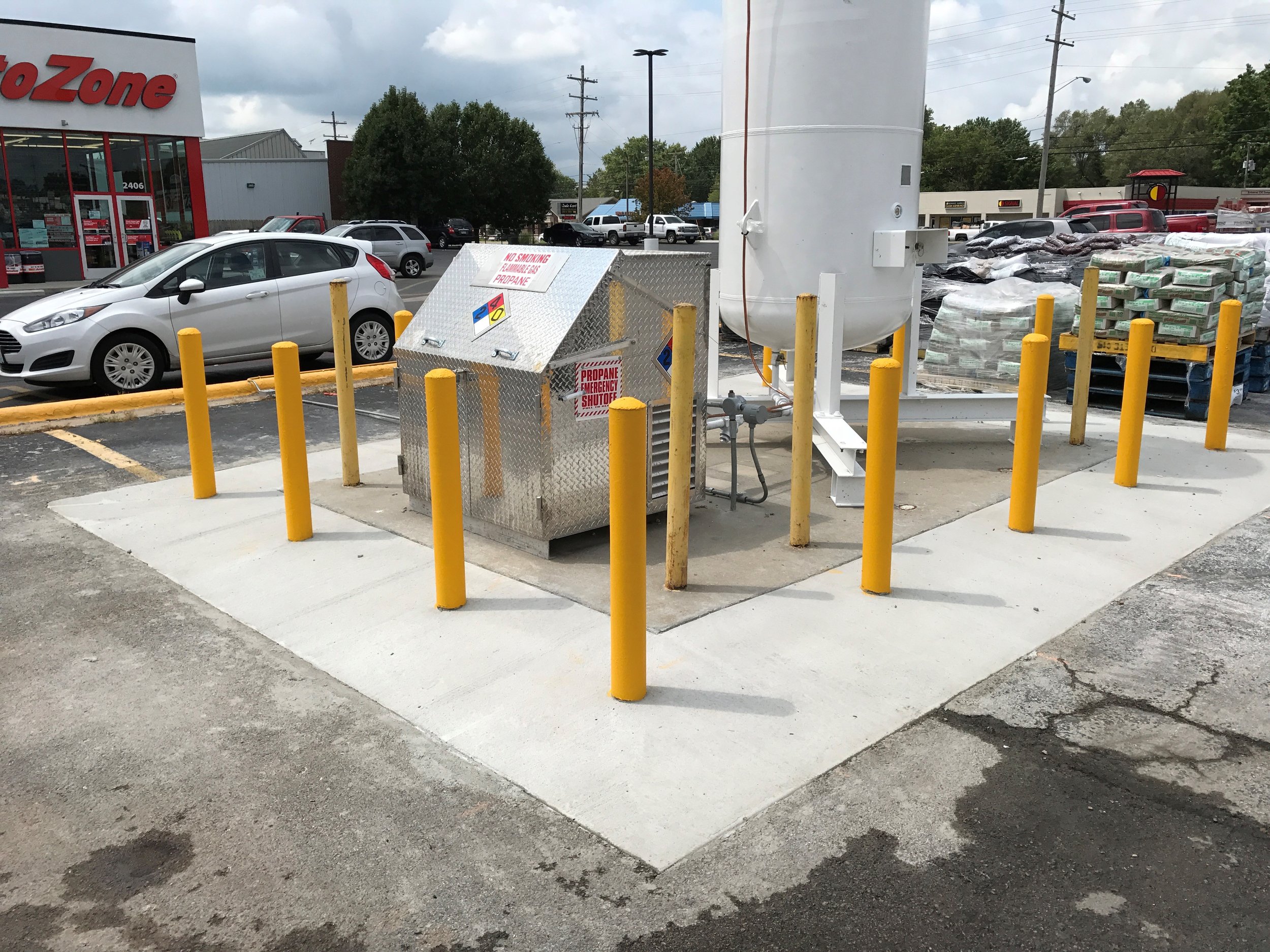 Concrete repair by Springfield Striping and Sealing in front of AutoZone with  safety bollards to protect a propane containment.