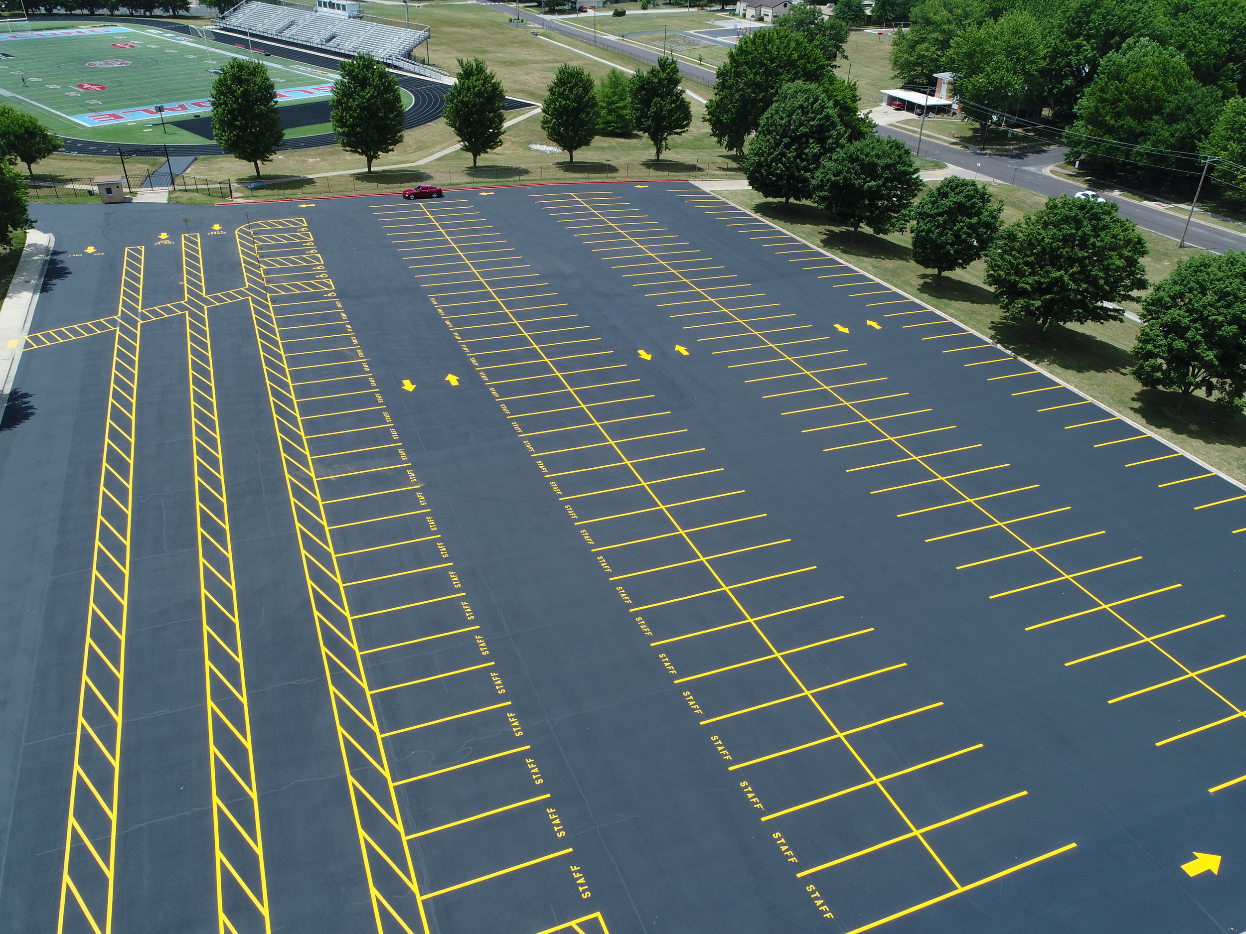 An aerial view of a large parking lot freshly painted bright yellow striping on a dark asphalt surface maintained by Springfield Striping and Sealing. 