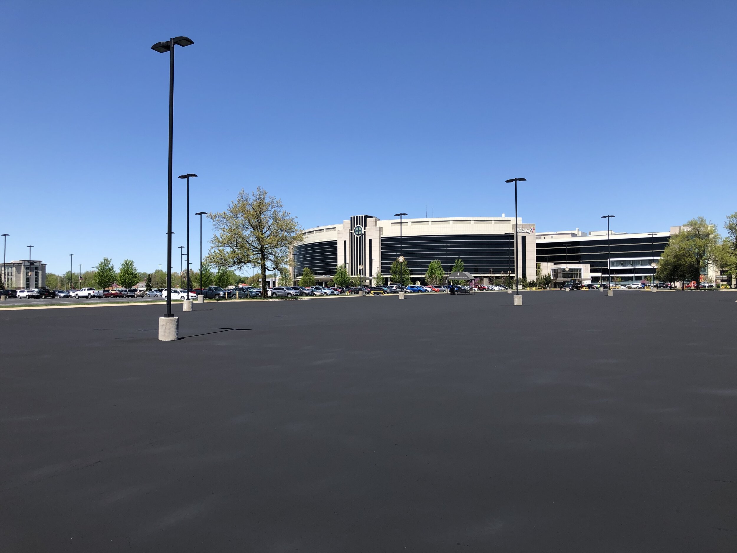 The expansive Mercy Hospital parking lot with freshly applied asphalt paving, showcasing a vast, open space with a uniform dark surface serviced by Springfield Striping and Sealing.