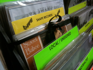 One of our stated aims when we set up Shape was to get our own section in Spillers Records, Cardiff so that we would no longer be in the 'local / unsigned" section. We achieved this goal in 2011. We got to cut the black ribbon to officially 'open' it. 