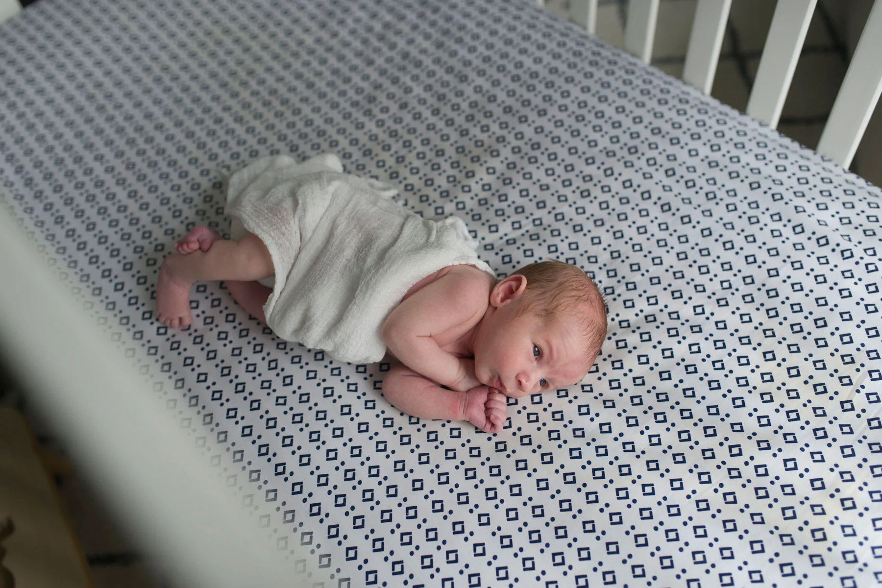 New_baby_boy_swaddled_in_crib_looking_out_indow.jpg