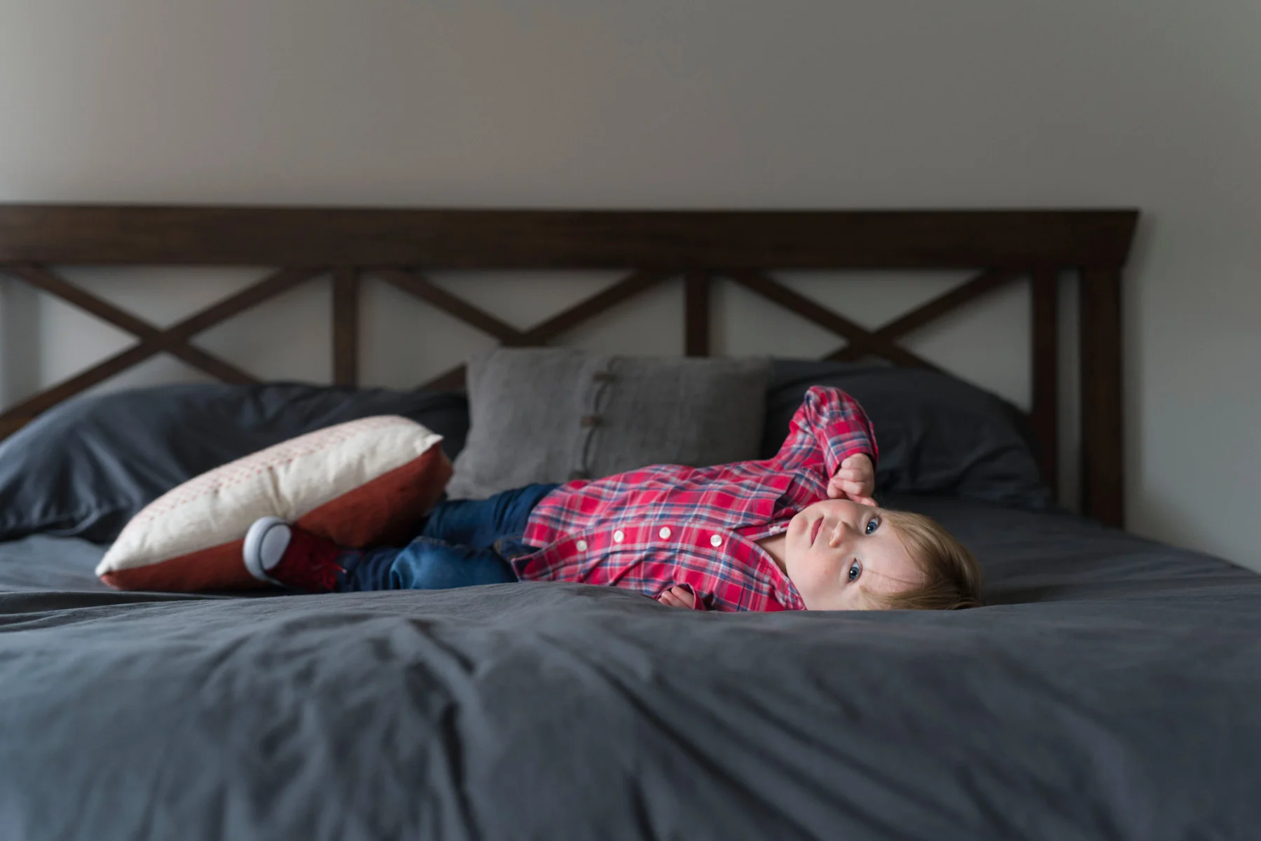 toddler_lays_on_parents_bed_looking_at_camera_upside_down.jpg