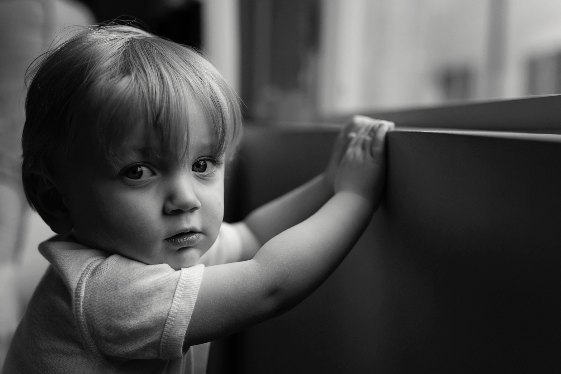 black_and_white_image_of_toddler_boy_looking_at_camera_by_window.jpg