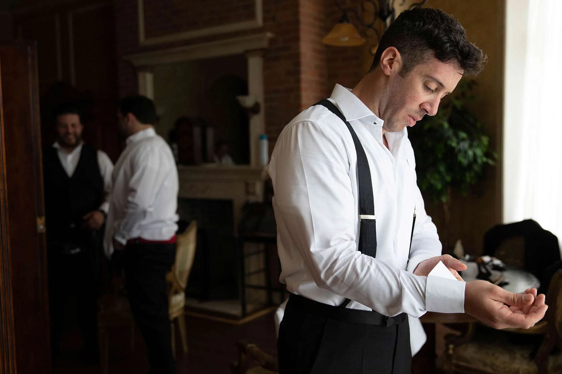 02_groom_adjusts_cuffs_at_Oheka_castle.jpg