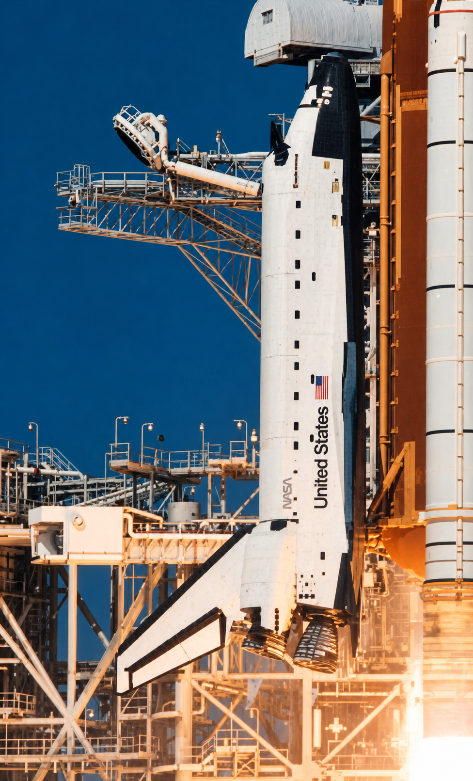 The Space Shuttle on the launch pad against a deep-blue sky, with the orange external tank and the service tower: reference for the shuttle hardware and the color palette.