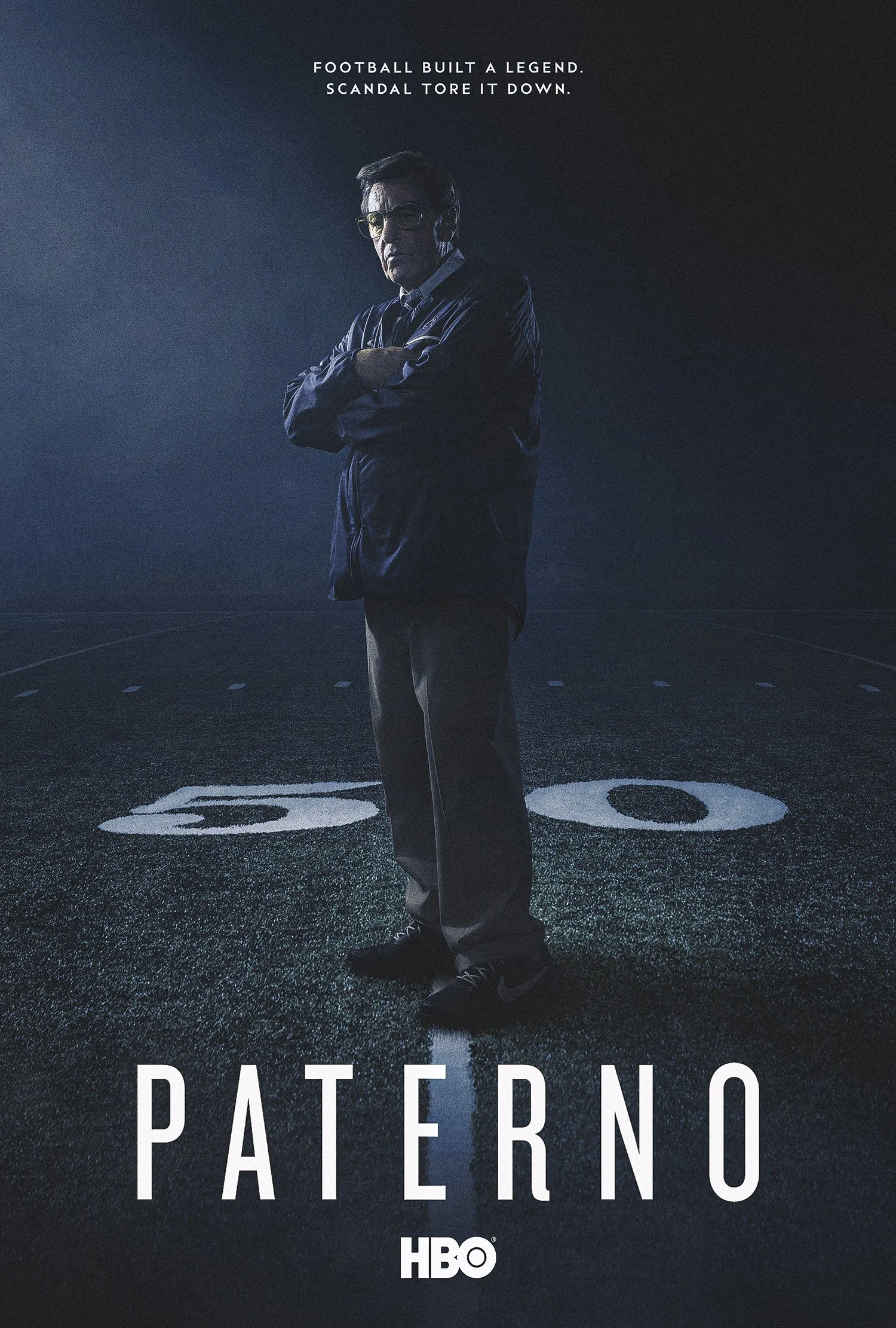 Paterno key art, direction B: a lone coach standing at the 50-yard line of a dark, empty football field.