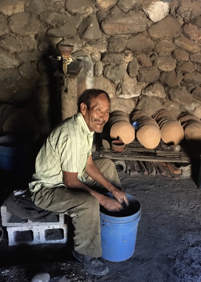 Maximilliano packing salt for sale. The clay bowls in the background are used to cook the salt in an open fire for 12 hours to get the crystal form.