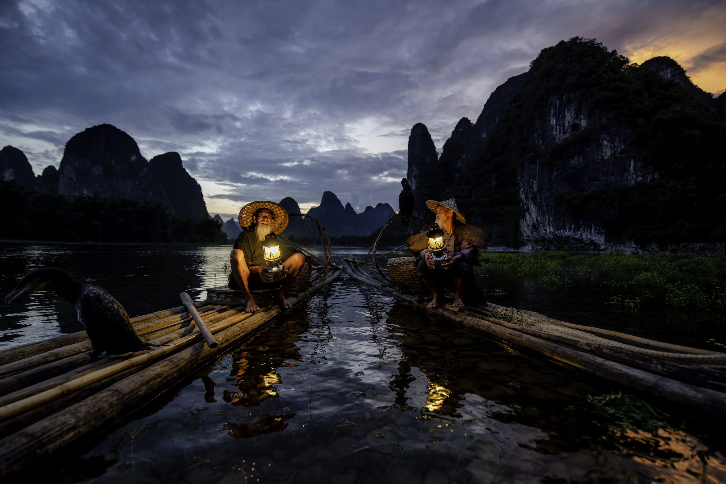 Two cormorant fishermen sit on their bamboo rafts on the Li River near Yangshuo, China.