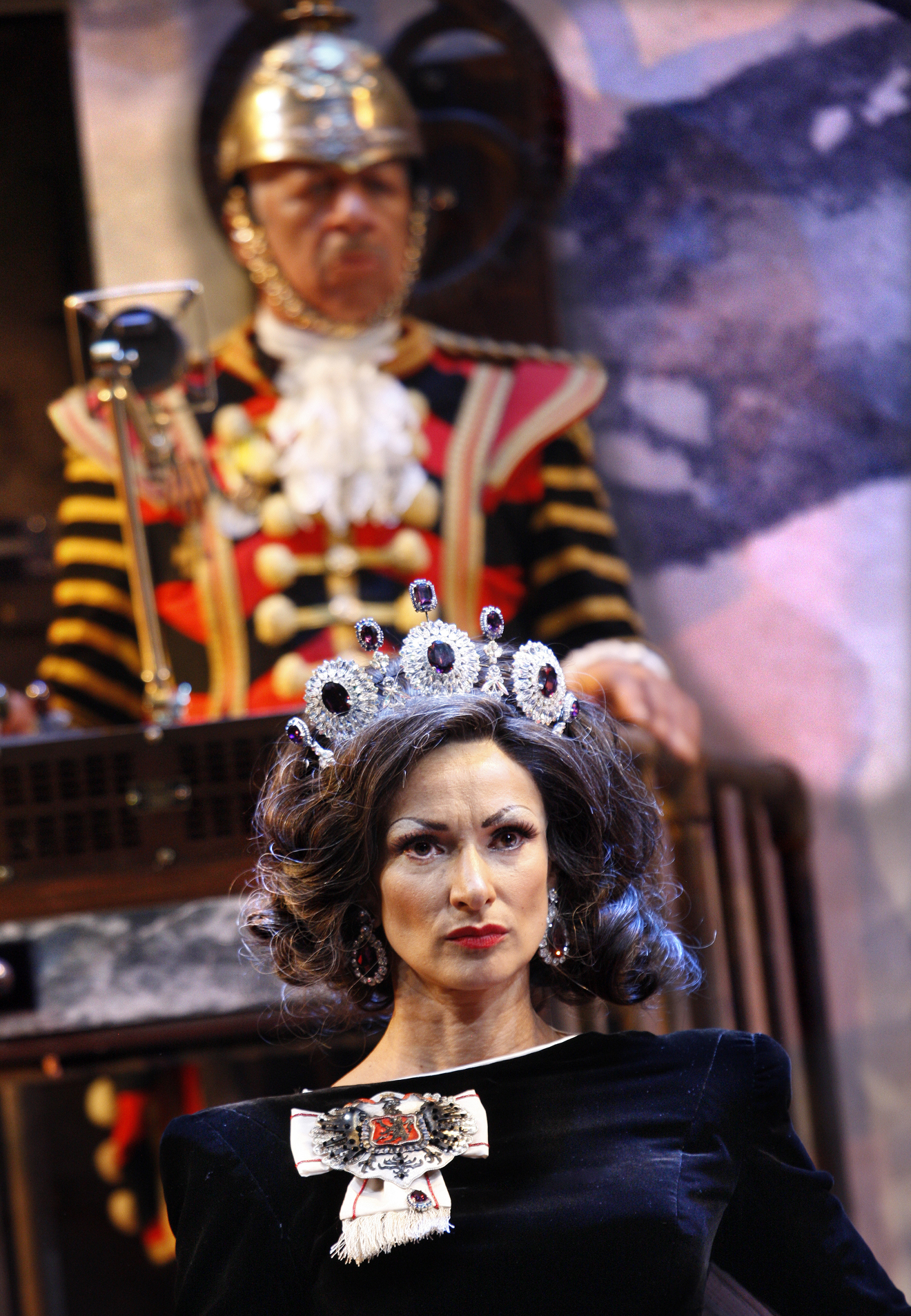 Exit the King foreground Indira Varma as Queen Marguerite background Derek Griffiths as the Guard in , photo by Simon Annand.JPG