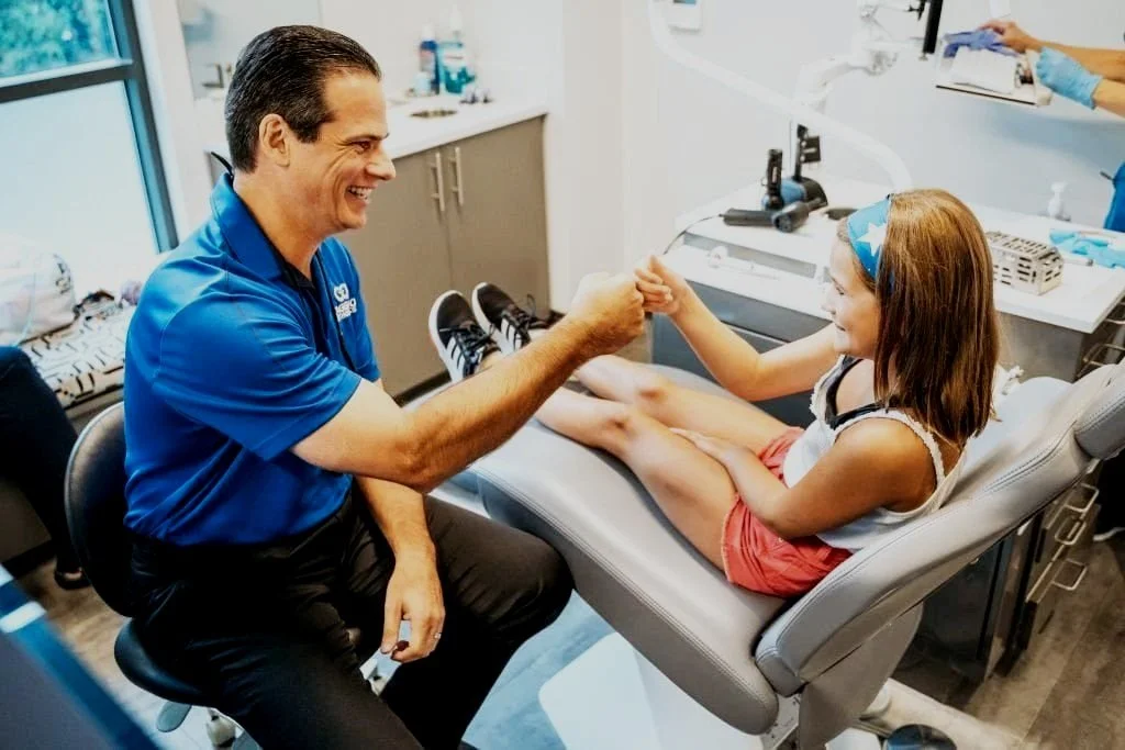 Orthodontist fist-bumping young patient in orthodontic treatment chair.jpg