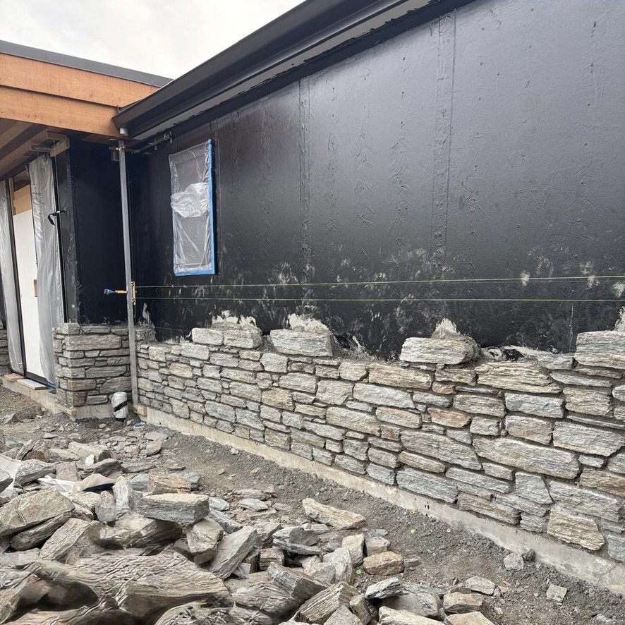 Natural stone cladding being installed on a Maddren Homes project in Weiti Bay