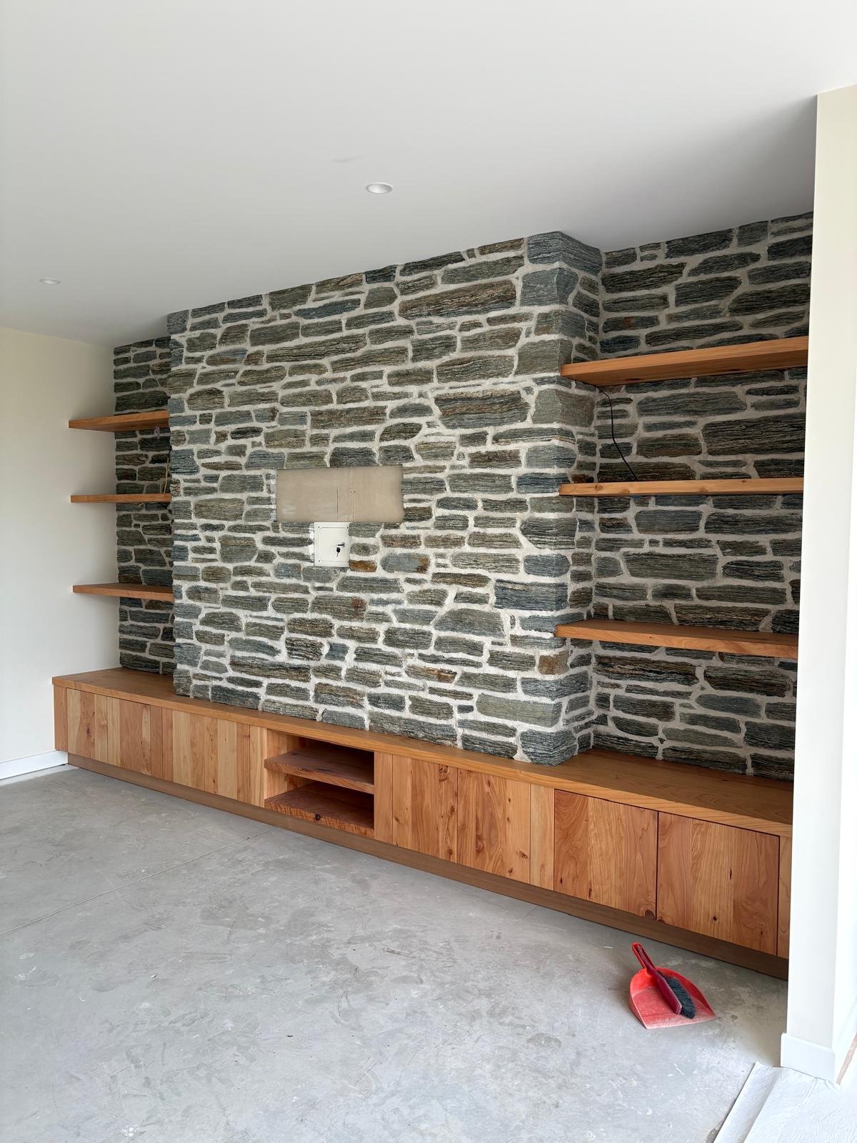 Natural stone feature wall and timber cabinetry inside a Maddren Homes project in Weiti Bay