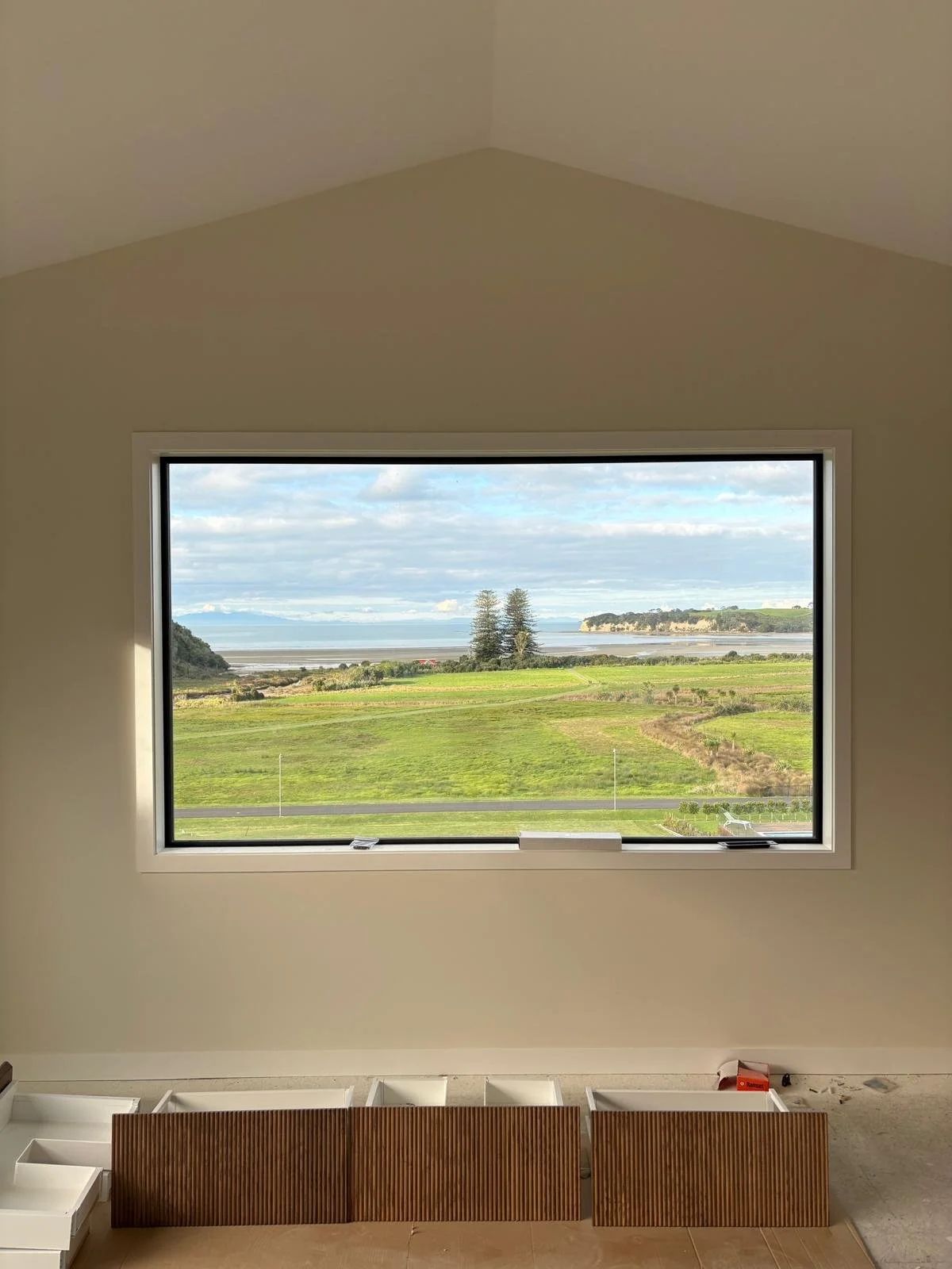 Coastal view framed by a large window in a Maddren Homes project at Weiti Bay