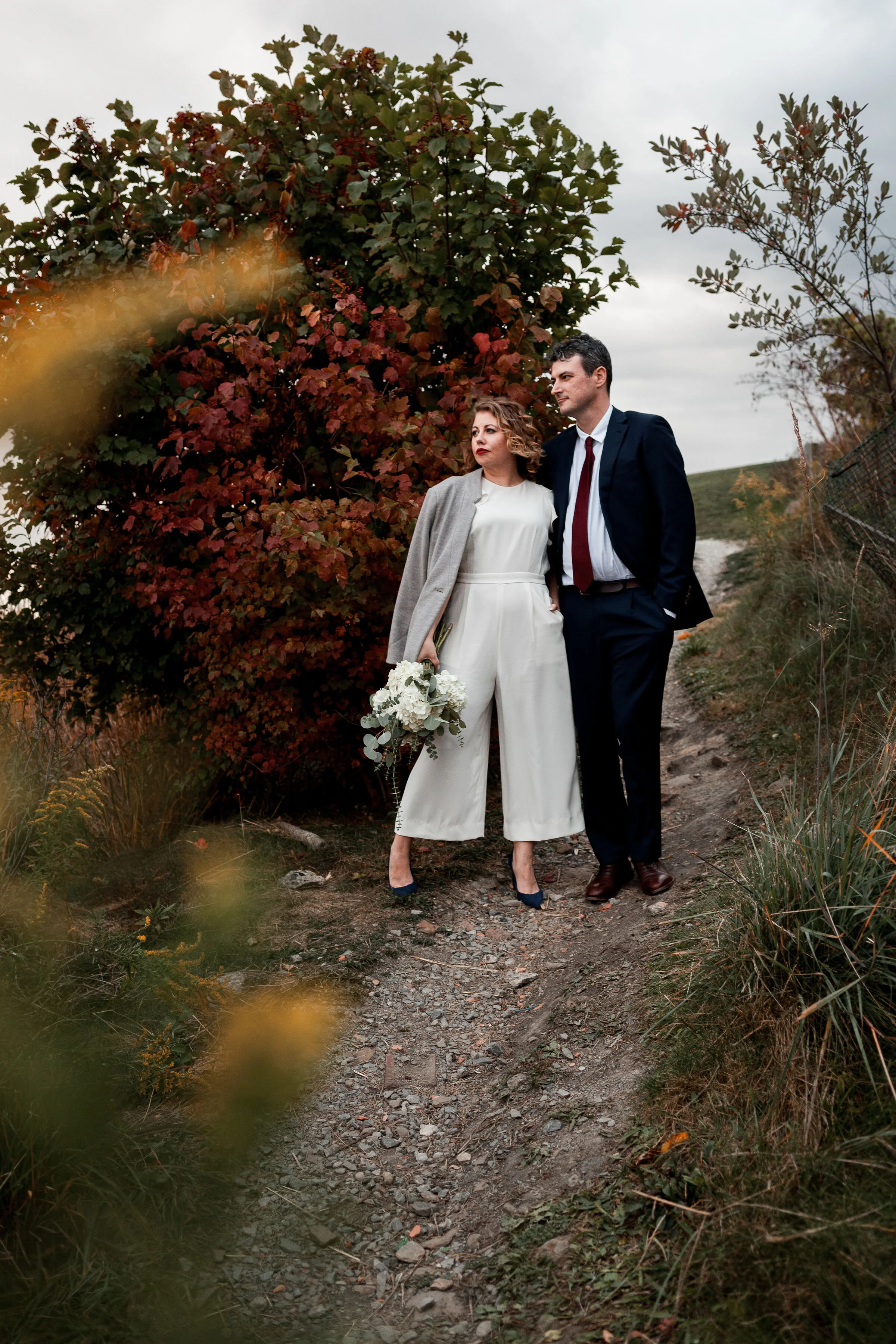 Bride wearing white pant suite standing with groom in Pittsburgh.