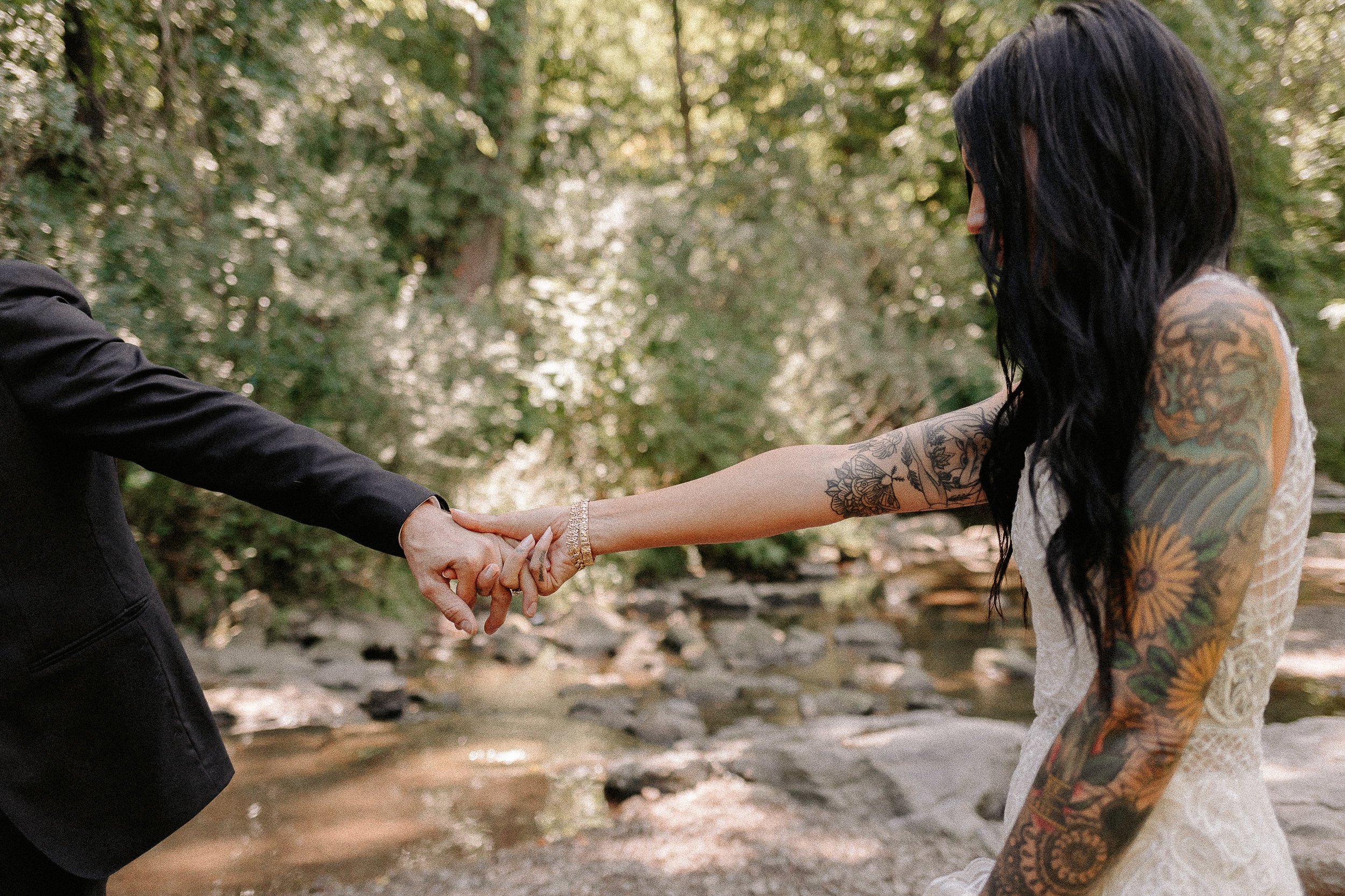 Couple holding hands with creek in the background.