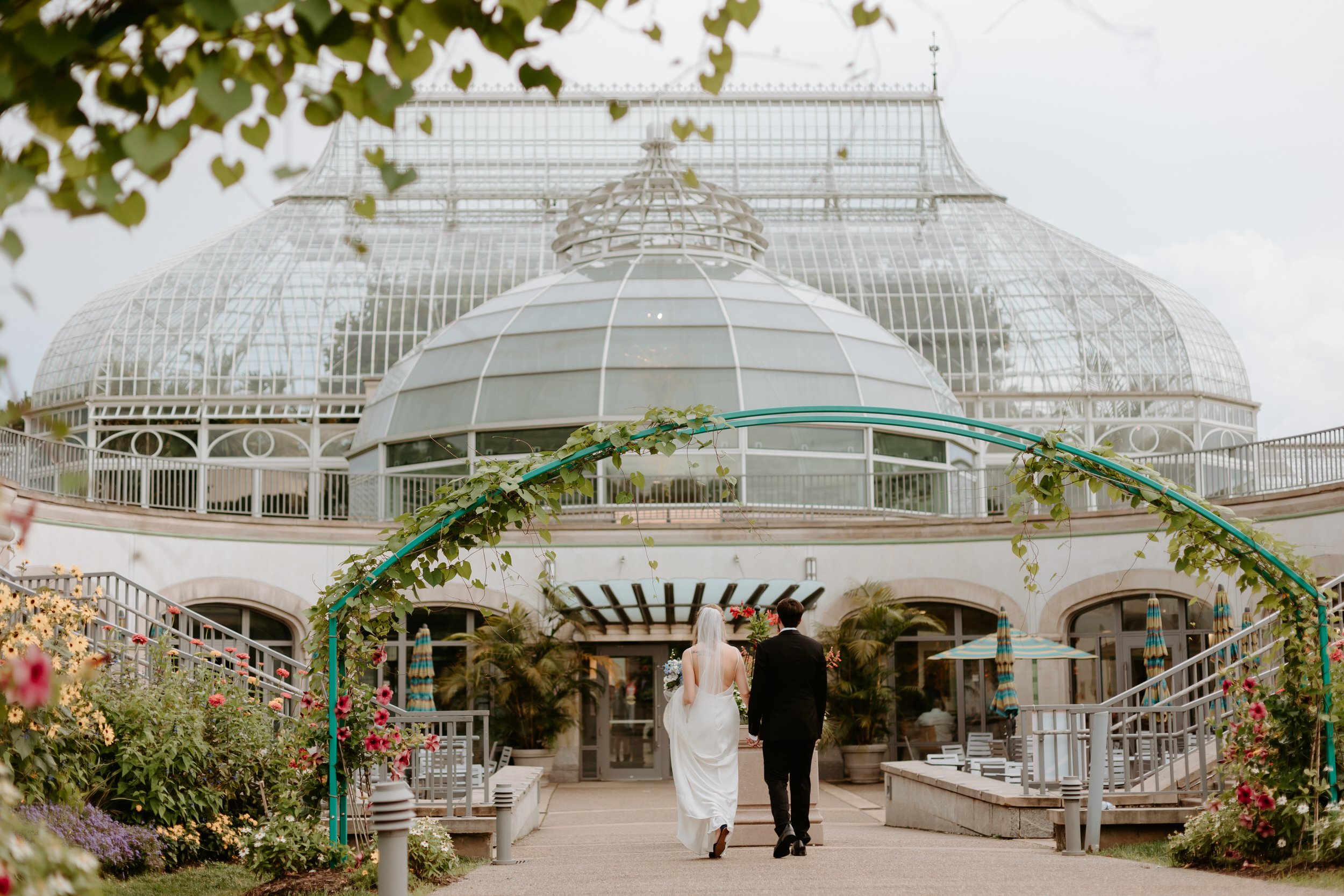 Man and woman walk holding hands in front of Phipps Conservatory.  