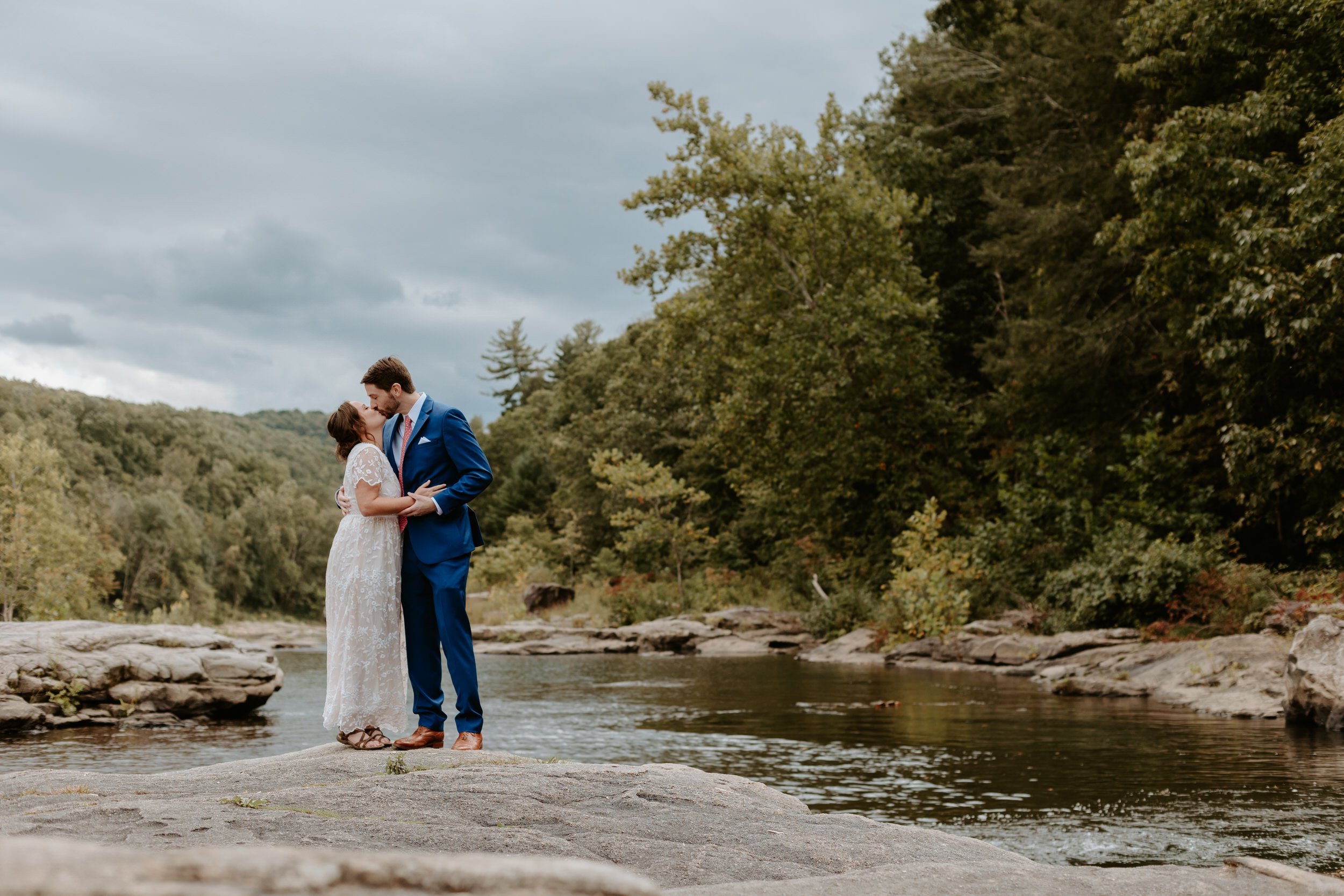 Couple kissing on flat rock near a river at Ohiopyle State Park.