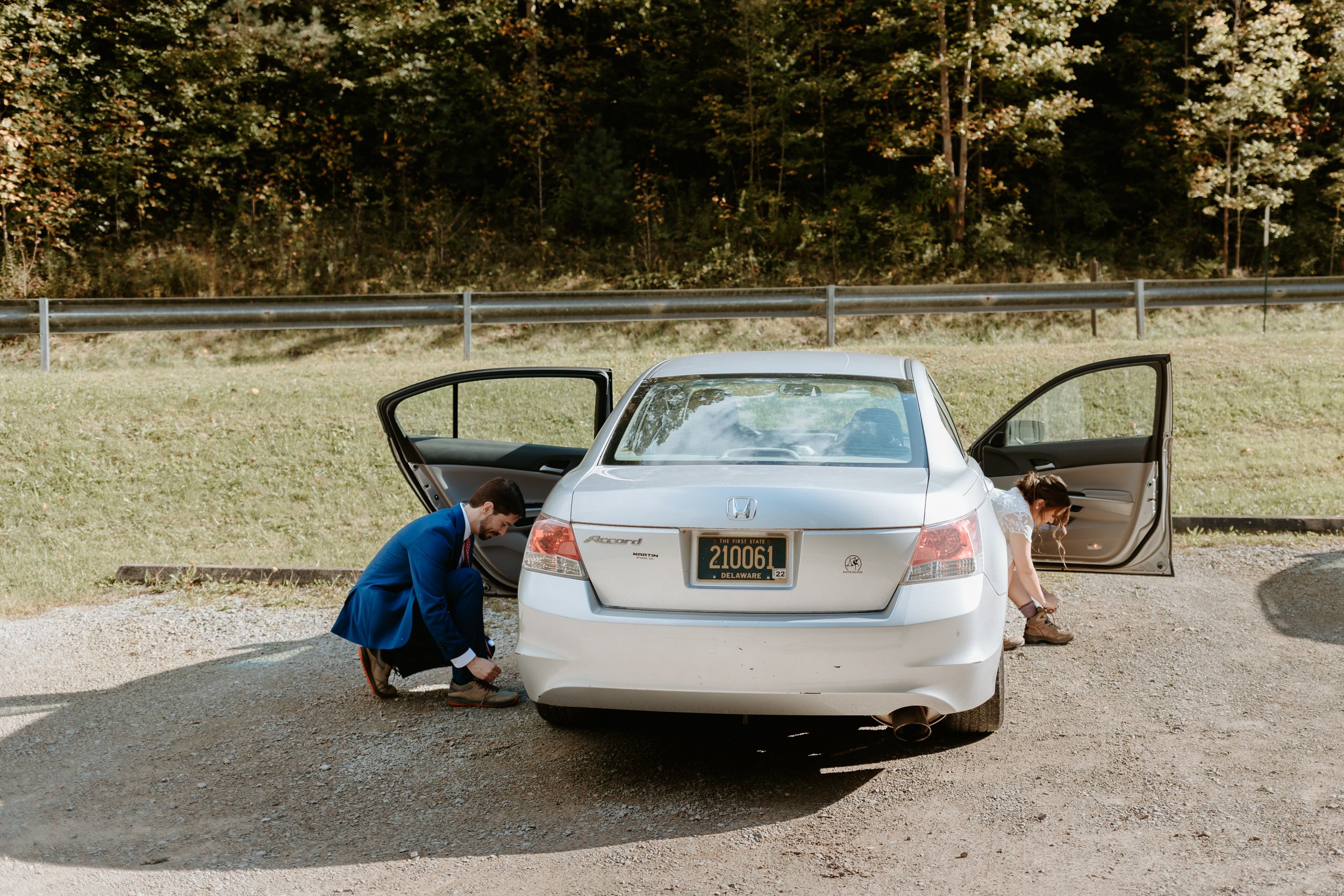 Couple putting on hiking boots at their car.