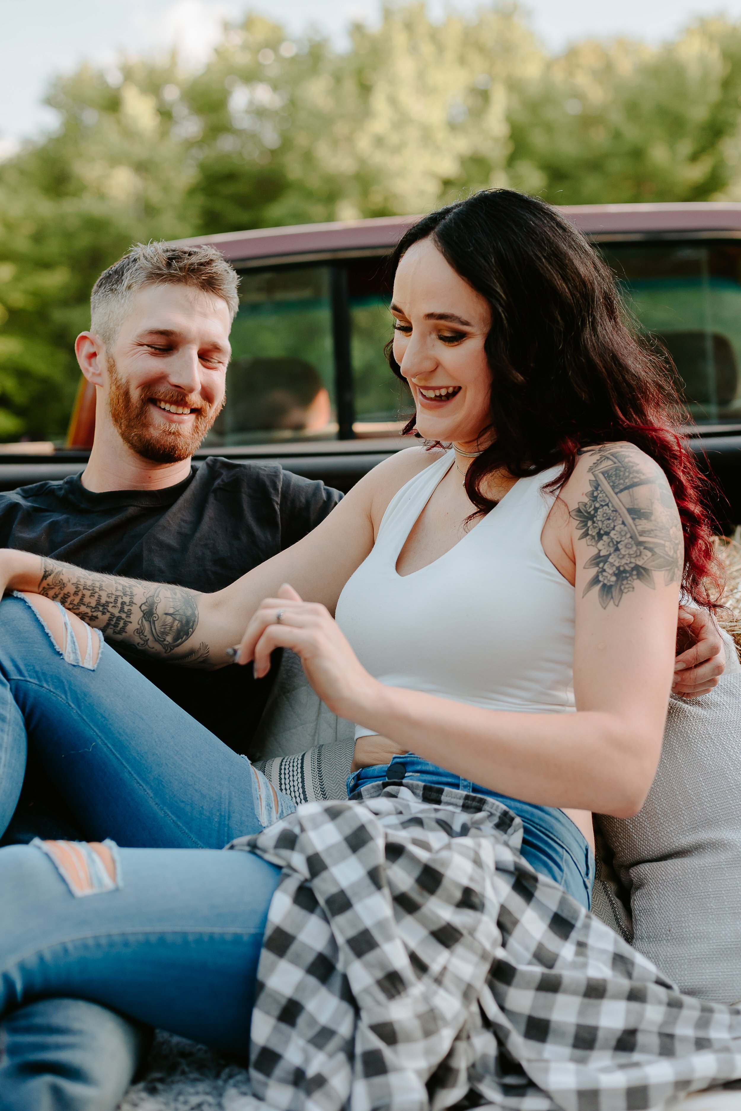 Couple laughs in the bed of a red truck.