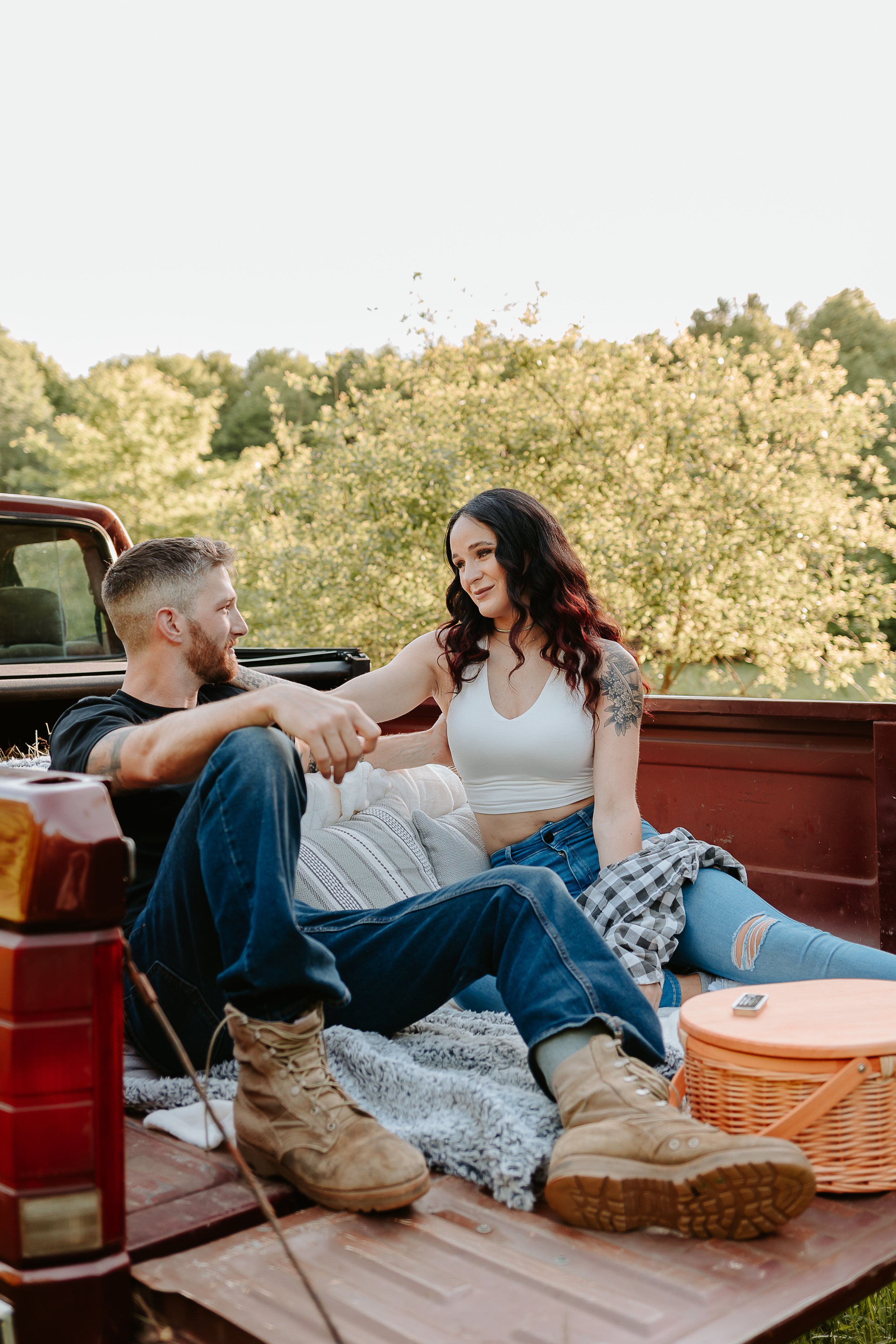Woman looks at man lovingly while sitting in bed of red truck.