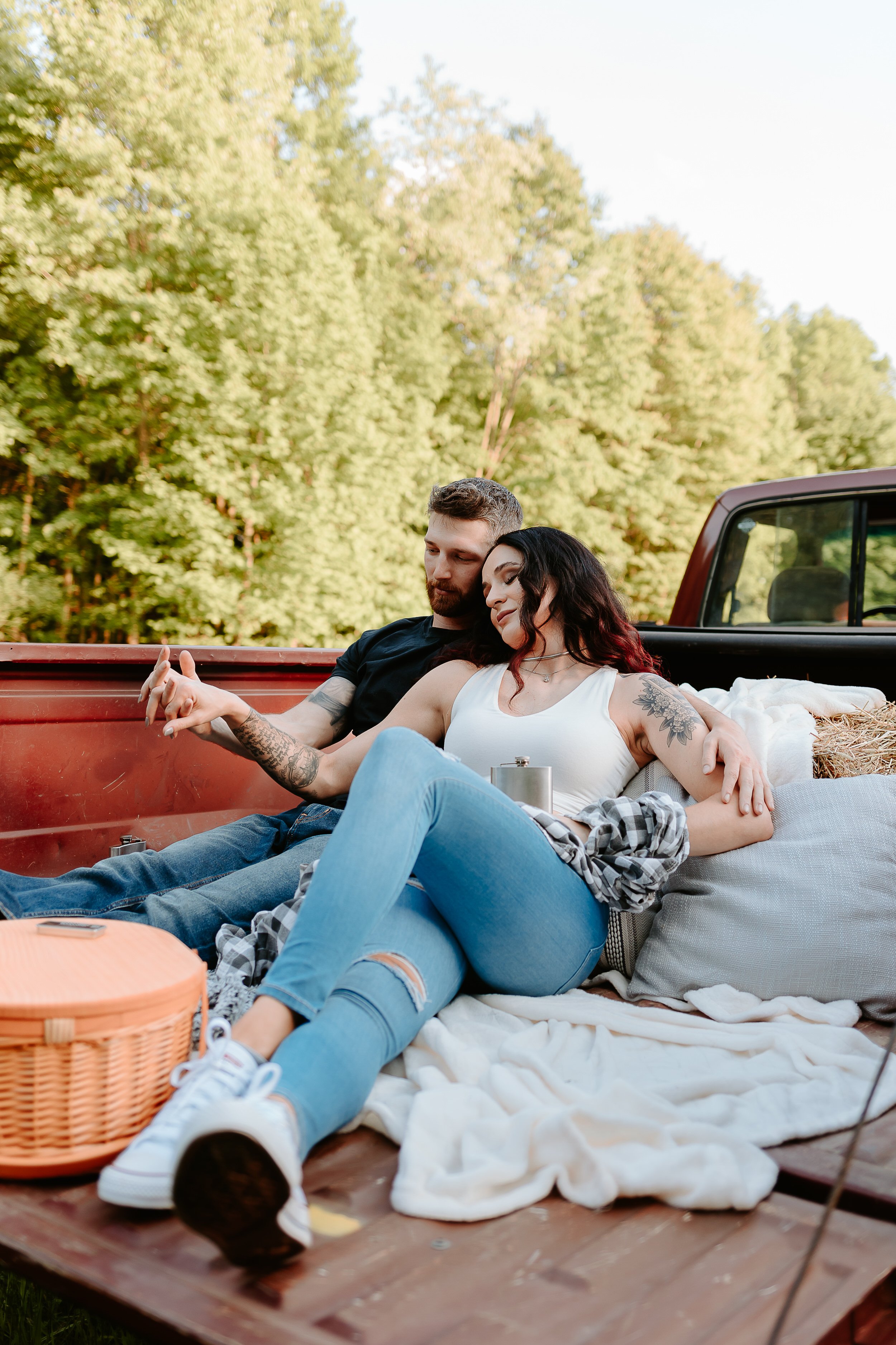 Couple cuddling in bed of red truck.
