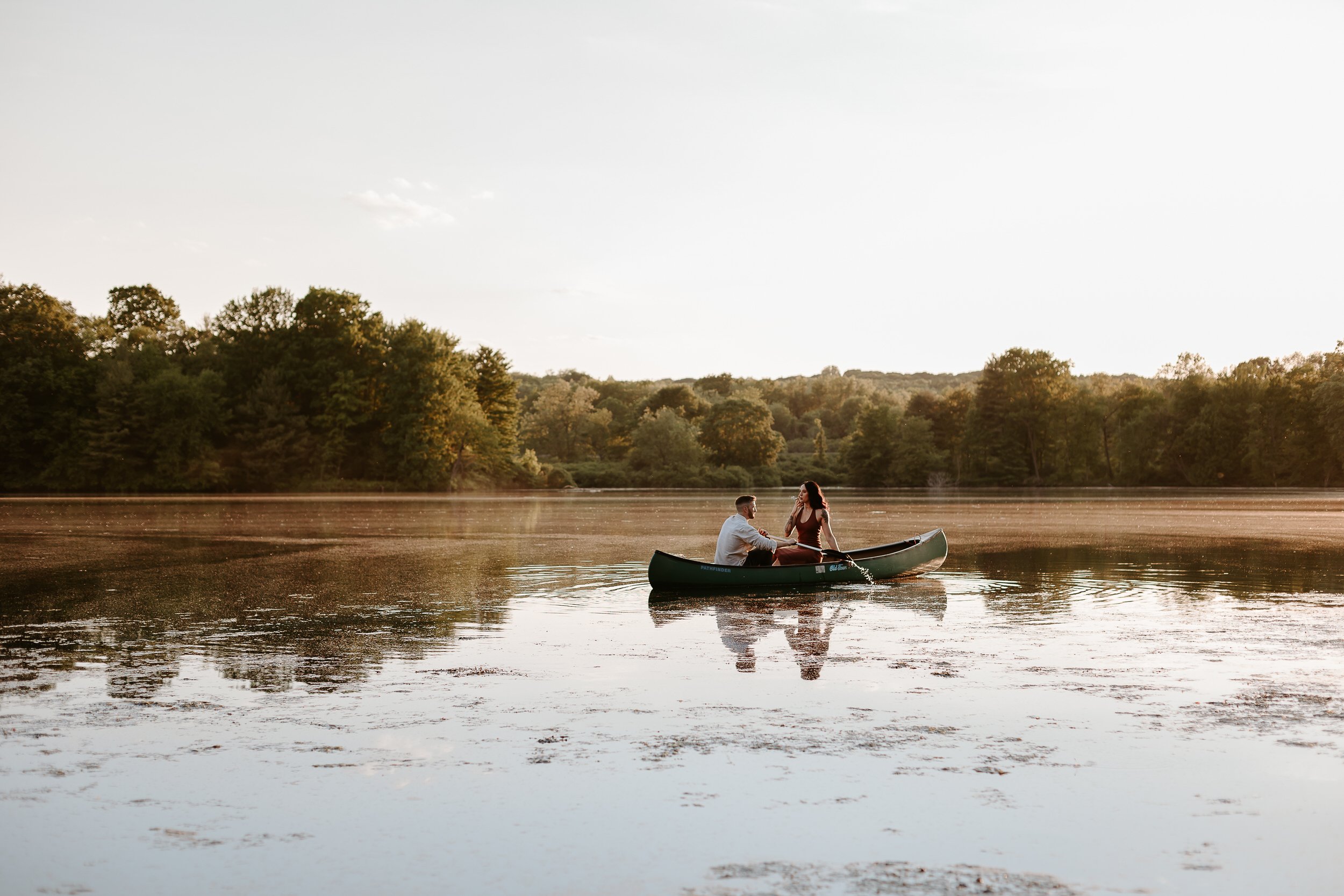 Man and woman are in a canoe out on a lake.
