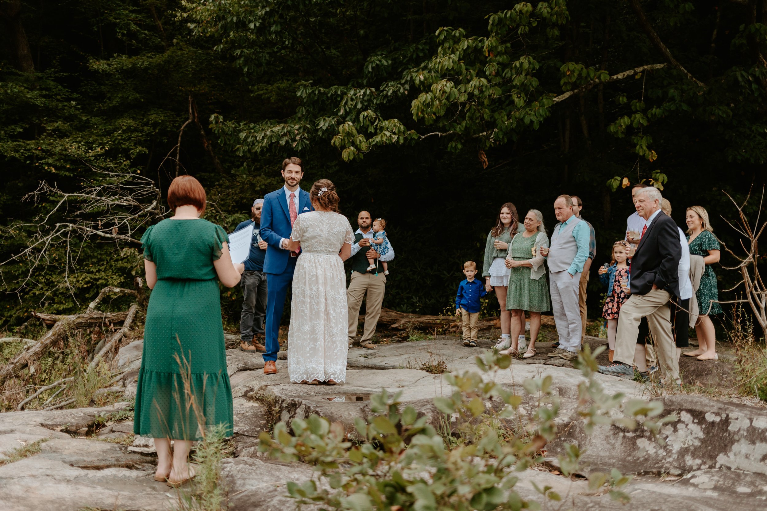 A wedding ceremony in the woods with a bride and groom.