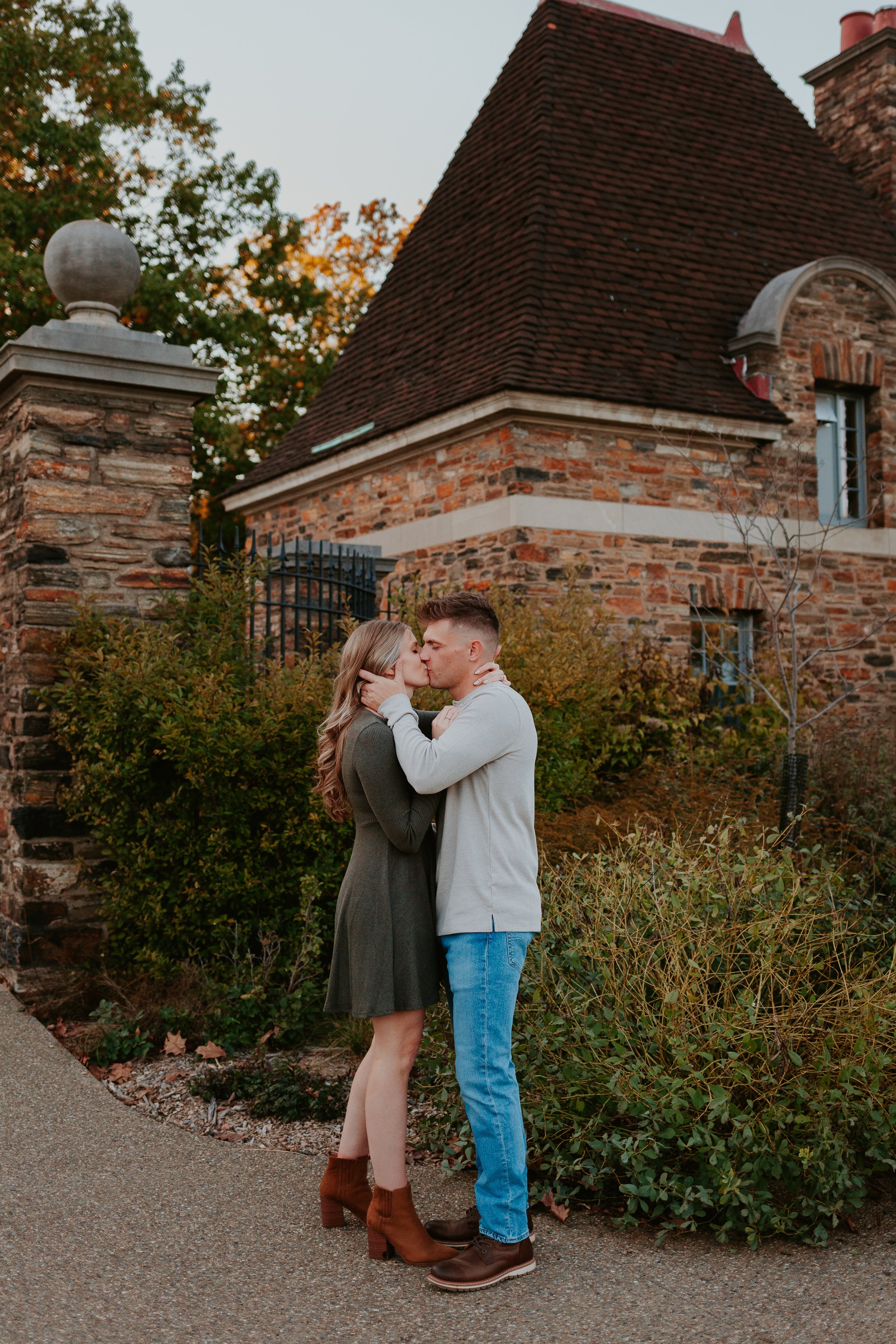 Couple kisses in front of brick building.