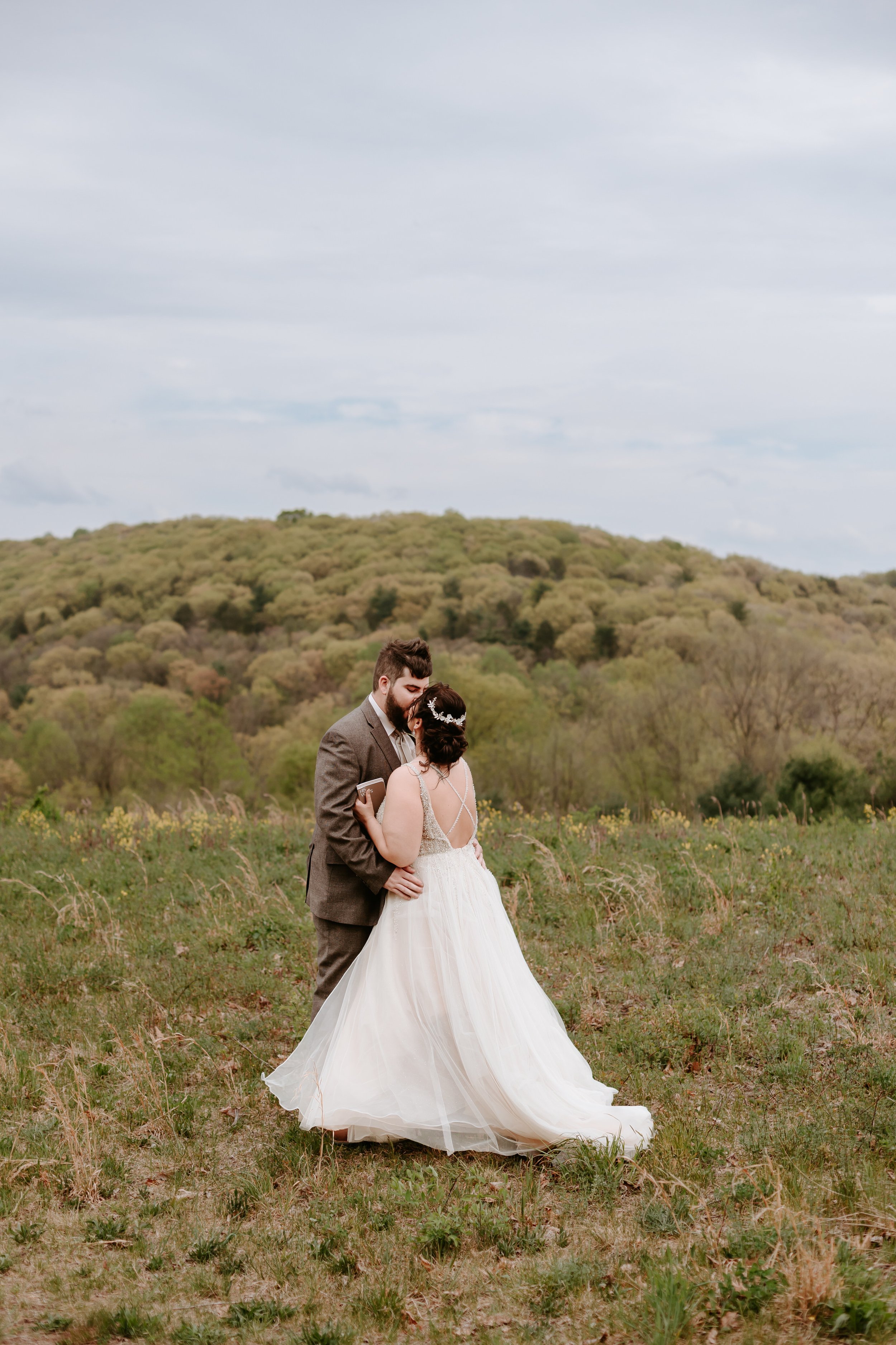 Bride and groom kiss in open landscape.