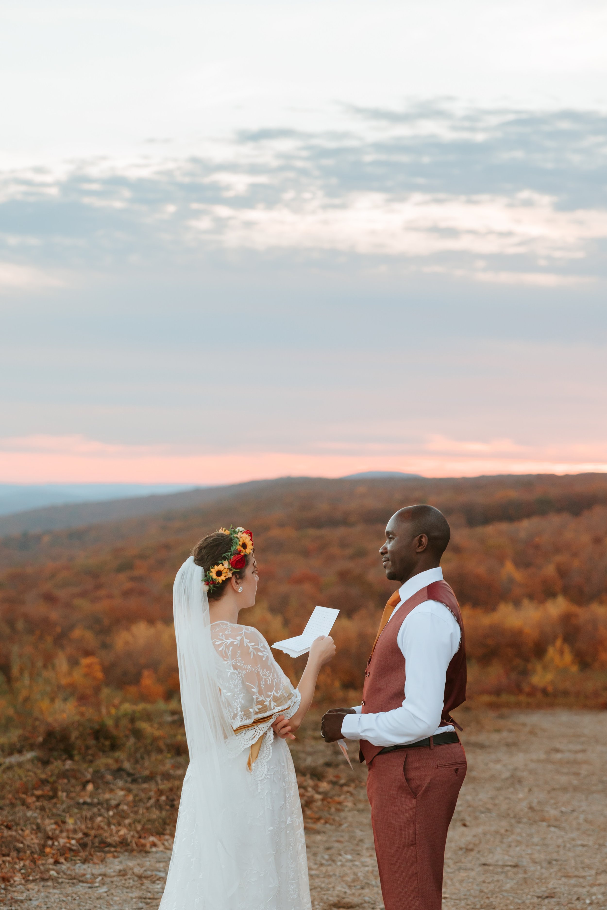 A bride and groom exchange vows in the mountains at sunset.