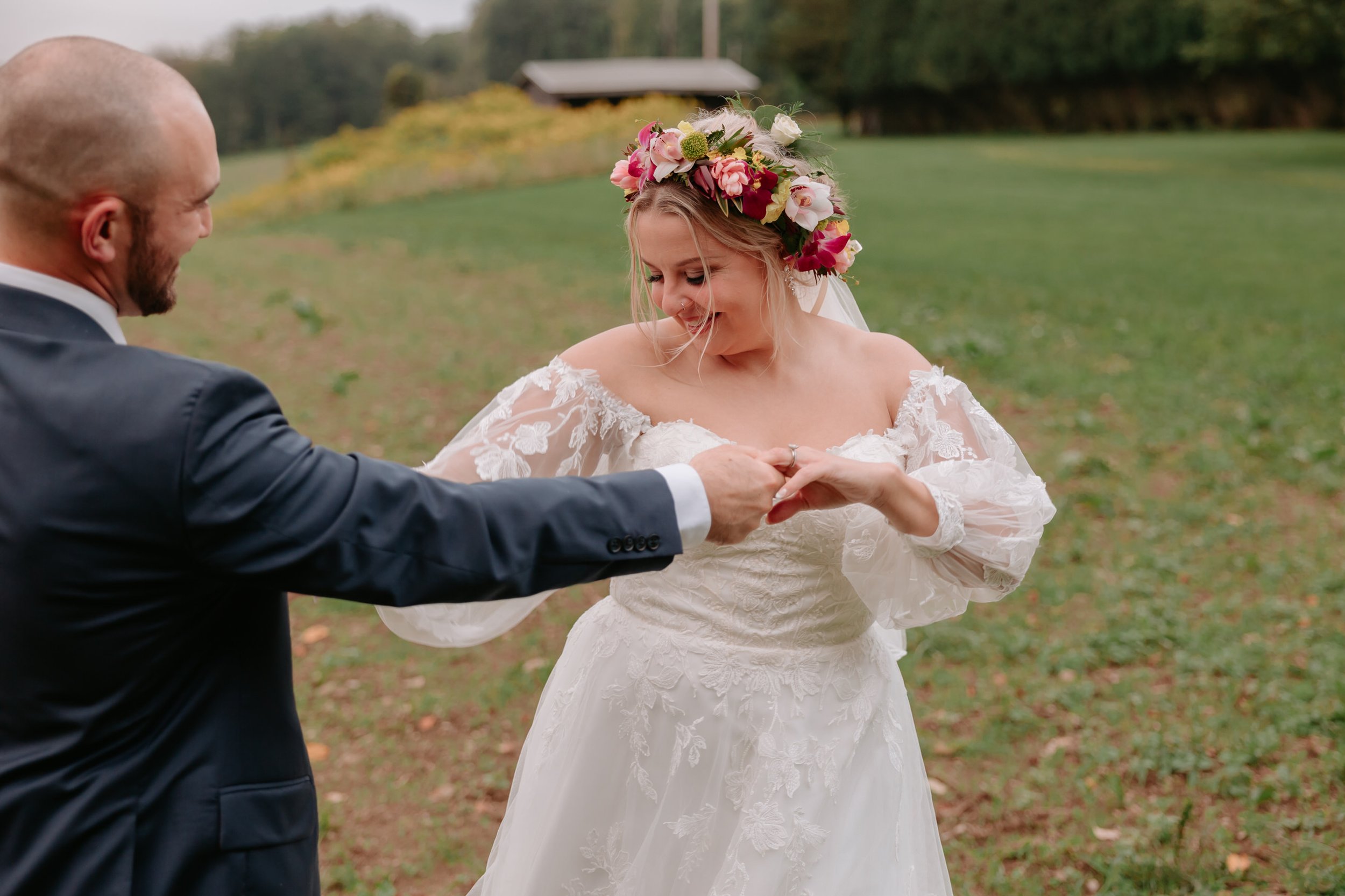 A bride and groom dancing in a field.