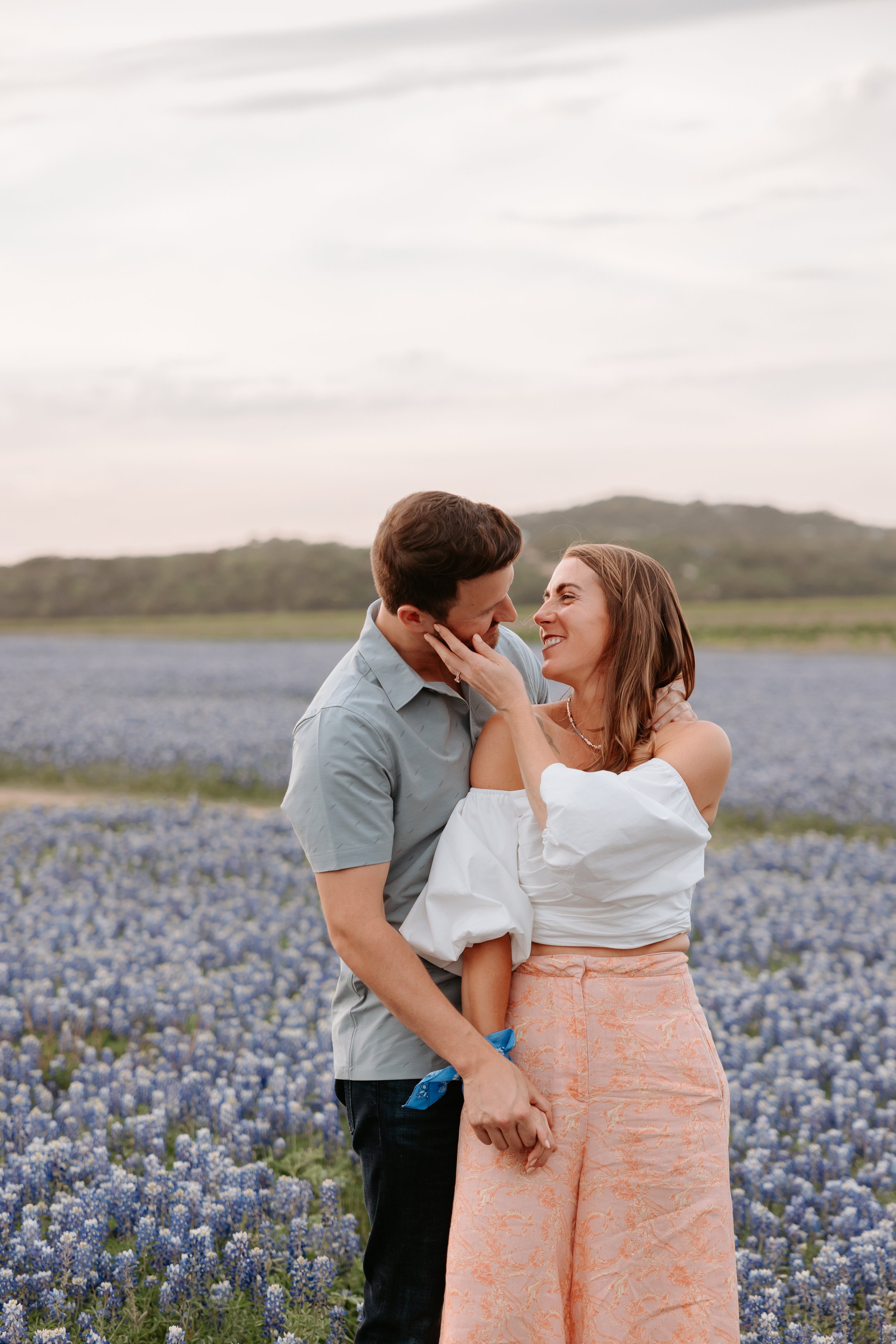 Man looks at woman in a field of blue flowers.