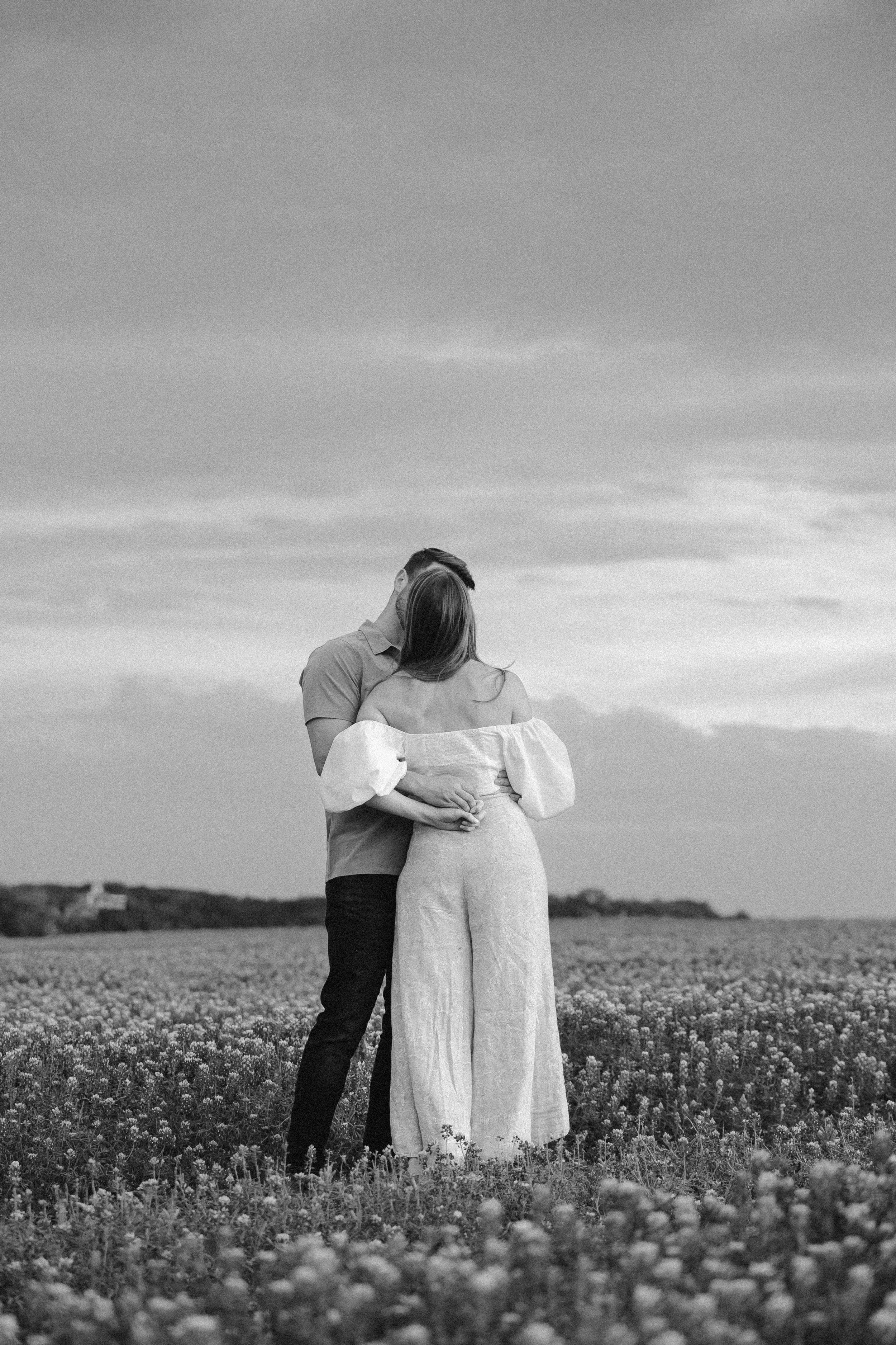 Man hugs woman in a field.