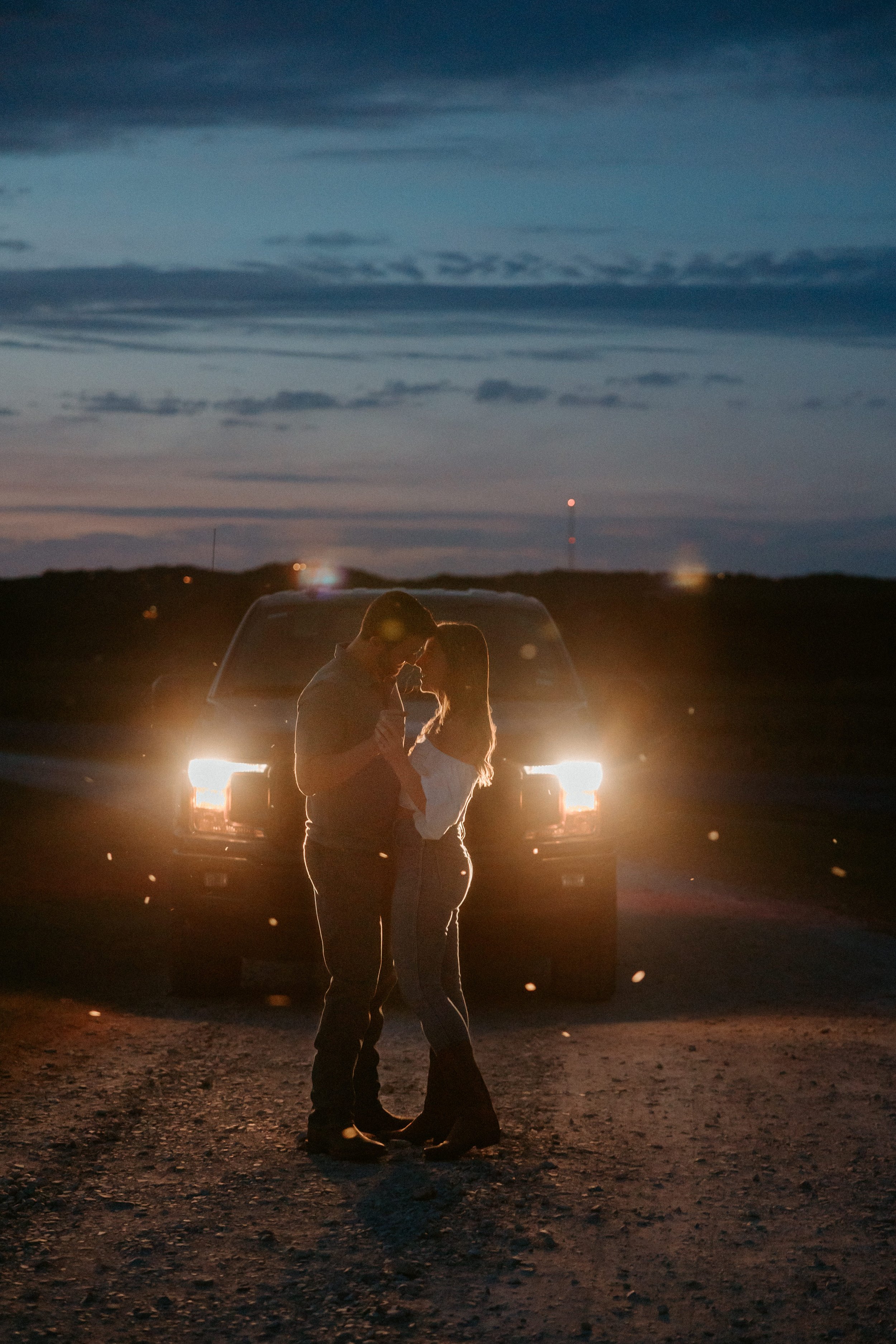Man and a woman dance in front of his truck.