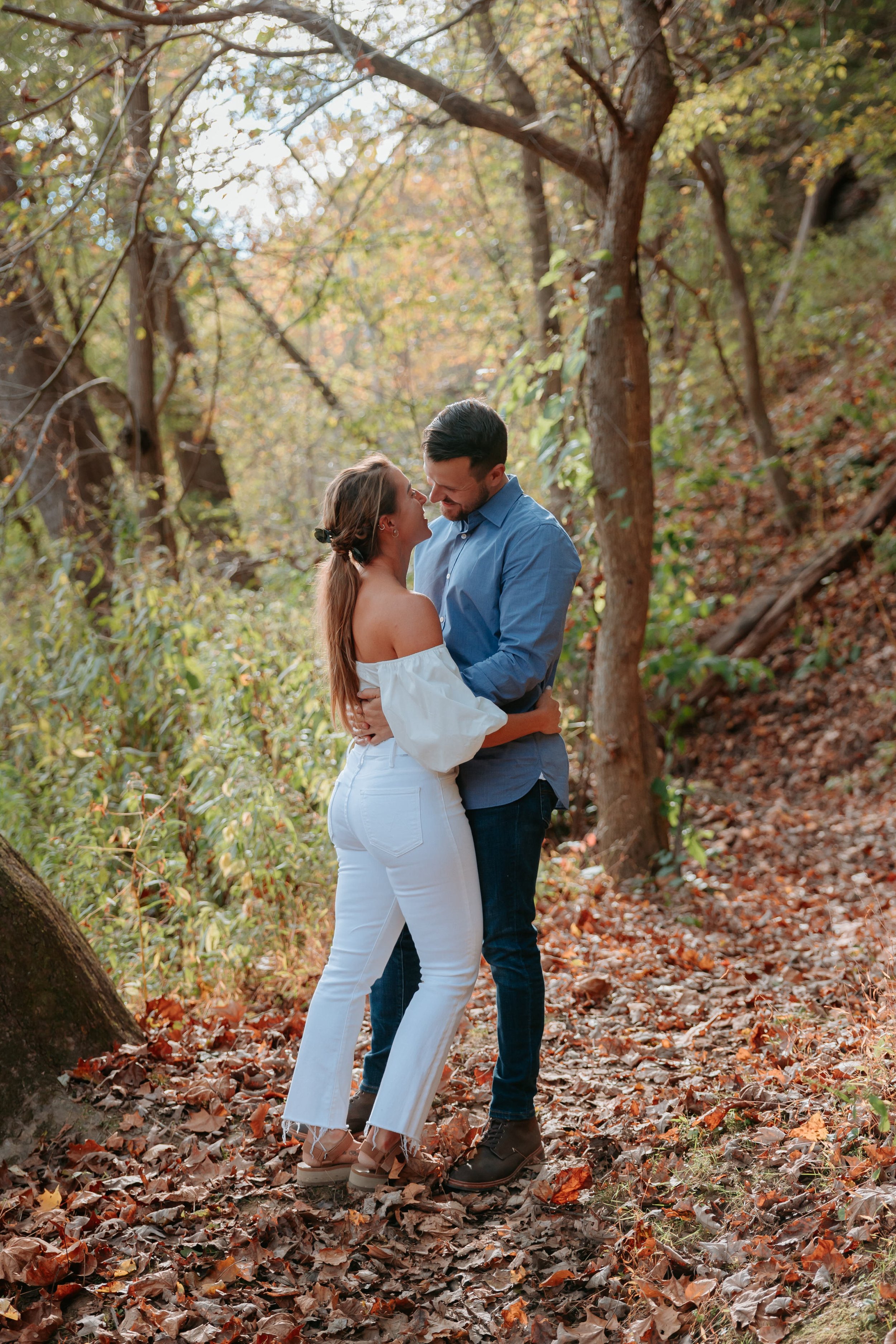 Man and woman embrace in forest.