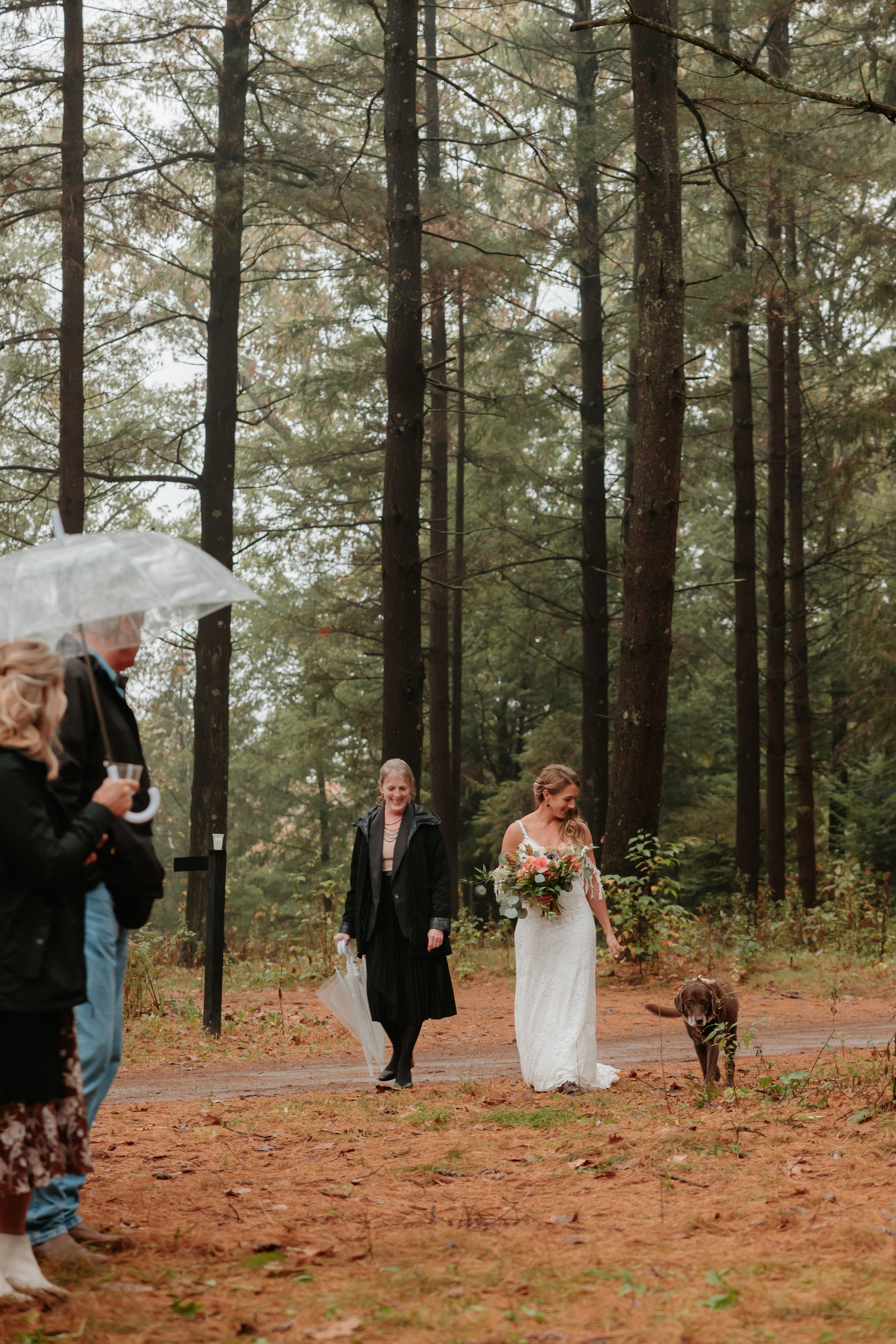 Bride walks down outside aisle with her dog.