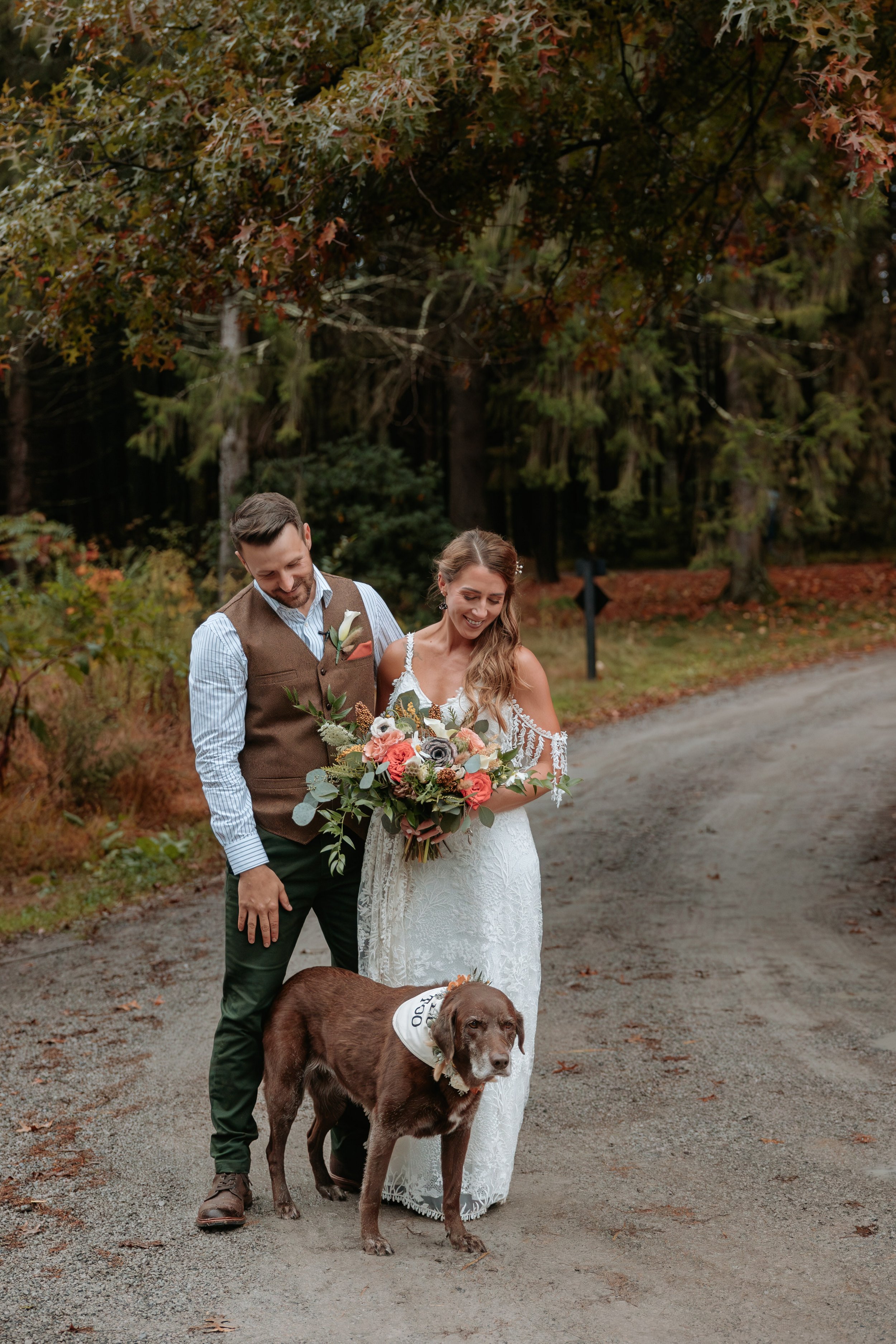 Bride and groom stand with their brown dog.